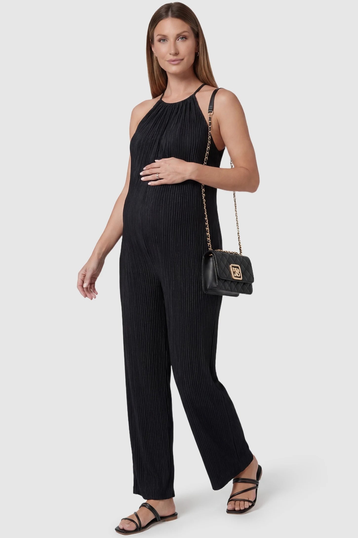 Halter Neck Wide Leg Pocketed Maternity Jumpsuit Halter Neck Wide Leg Pocketed Maternity Jumpsuit in Black featuring a gathered halter neck and ribbed texture on a pregnant model, styled lifestyle view.
