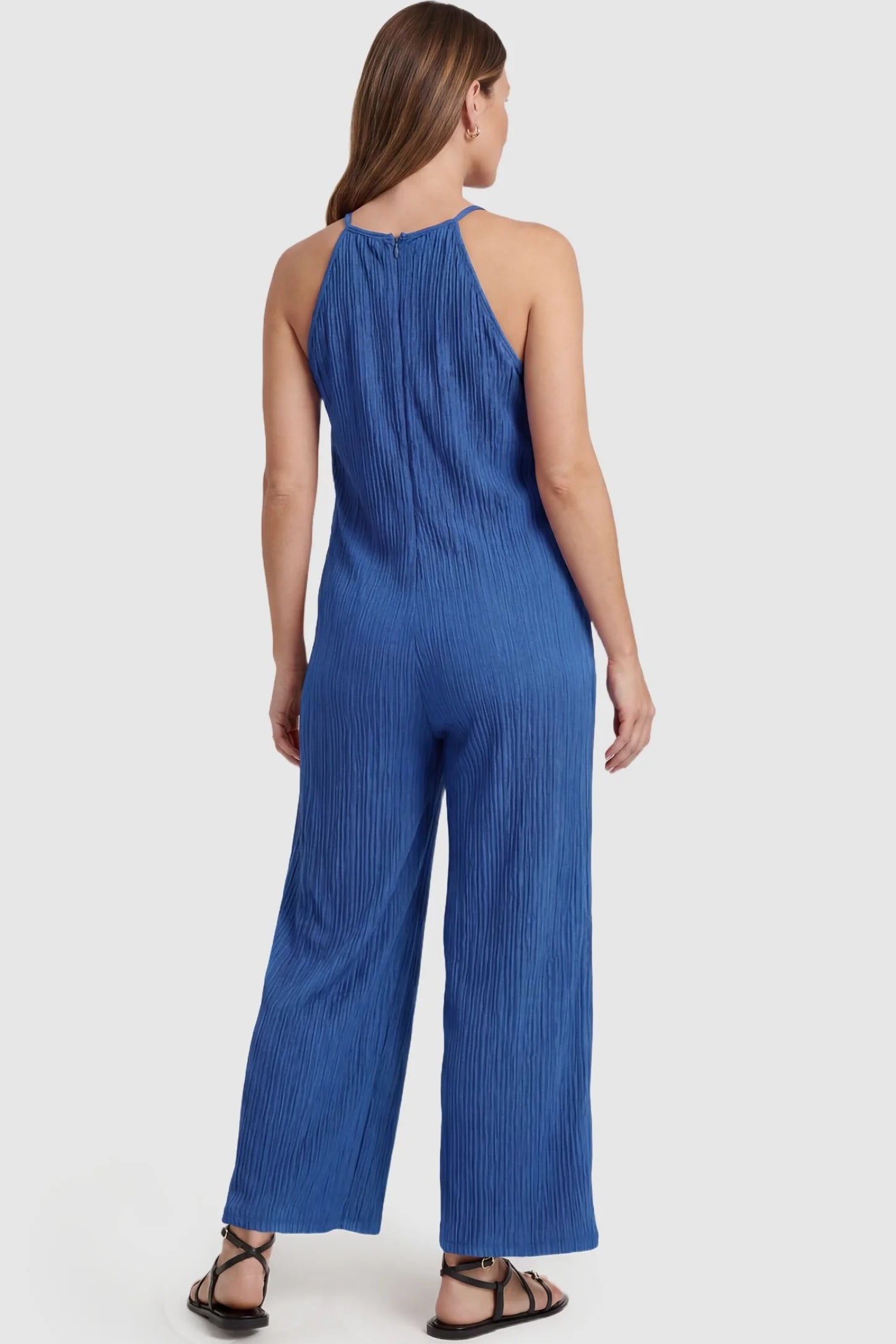 Halter Neck Wide Leg Pocketed Maternity Jumpsuit Halter Neck Wide Leg Pocketed Maternity Jumpsuit in Blue featuring a halter neck and allover ribbing on a pregnant model, back view.