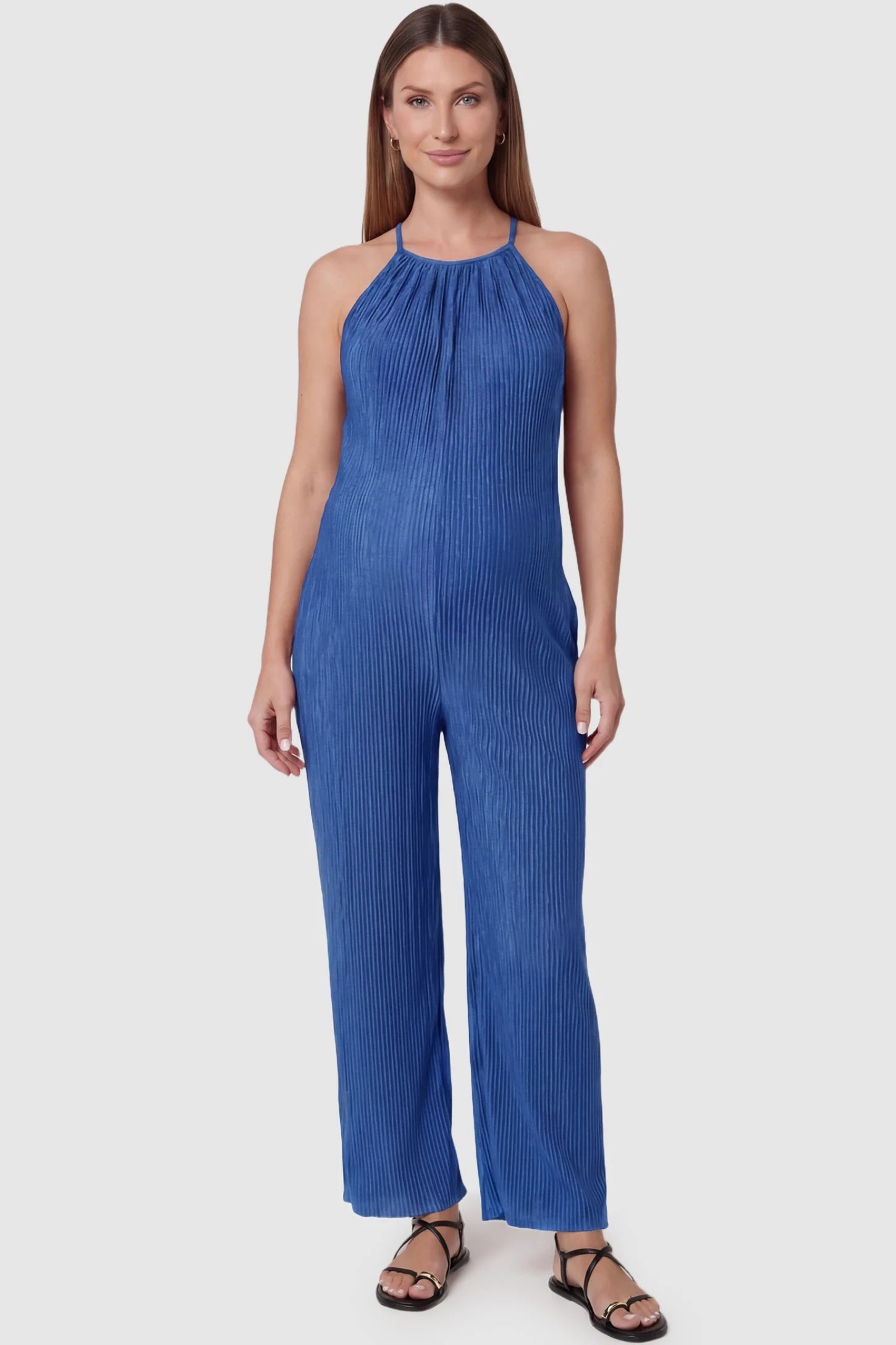 Halter Neck Wide Leg Pocketed Maternity Jumpsuit Halter Neck Wide Leg Pocketed Maternity Jumpsuit in Blue featuring a gathered halter neck and ribbed texture on a pregnant model, front view.