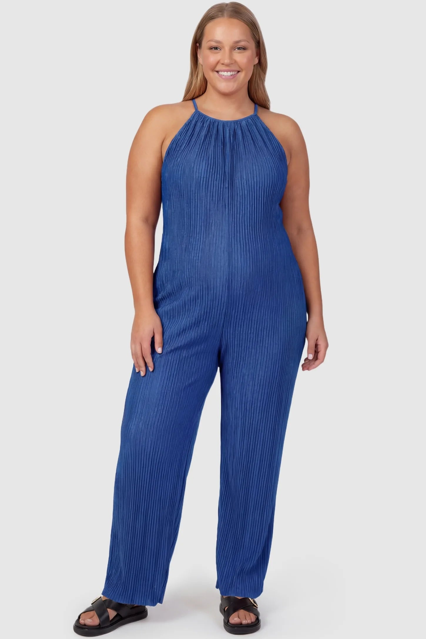 Halter Neck Wide Leg Pocketed Maternity Jumpsuit Halter Neck Wide Leg Pocketed Maternity Jumpsuit in Blue featuring a gathered halter neck and ribbed texture on a plus-size pregnant model, front view.