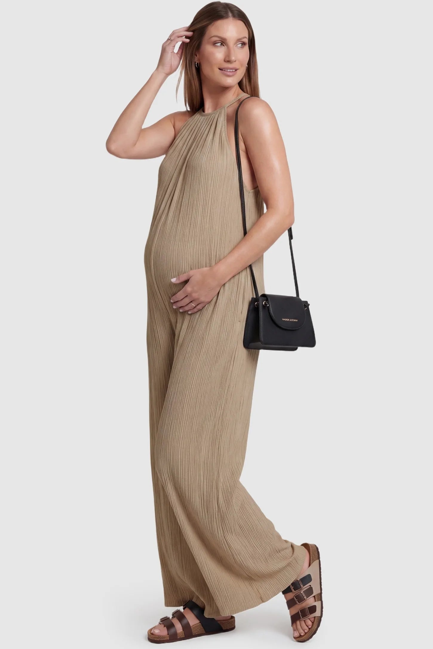 Halter Neck Wide Leg Pocketed Maternity Jumpsuit Halter Neck Wide Leg Pocketed Maternity Jumpsuit in Khaki featuring a gathered halter neck and ribbed texture on a pregnant model, styled lifestyle view.