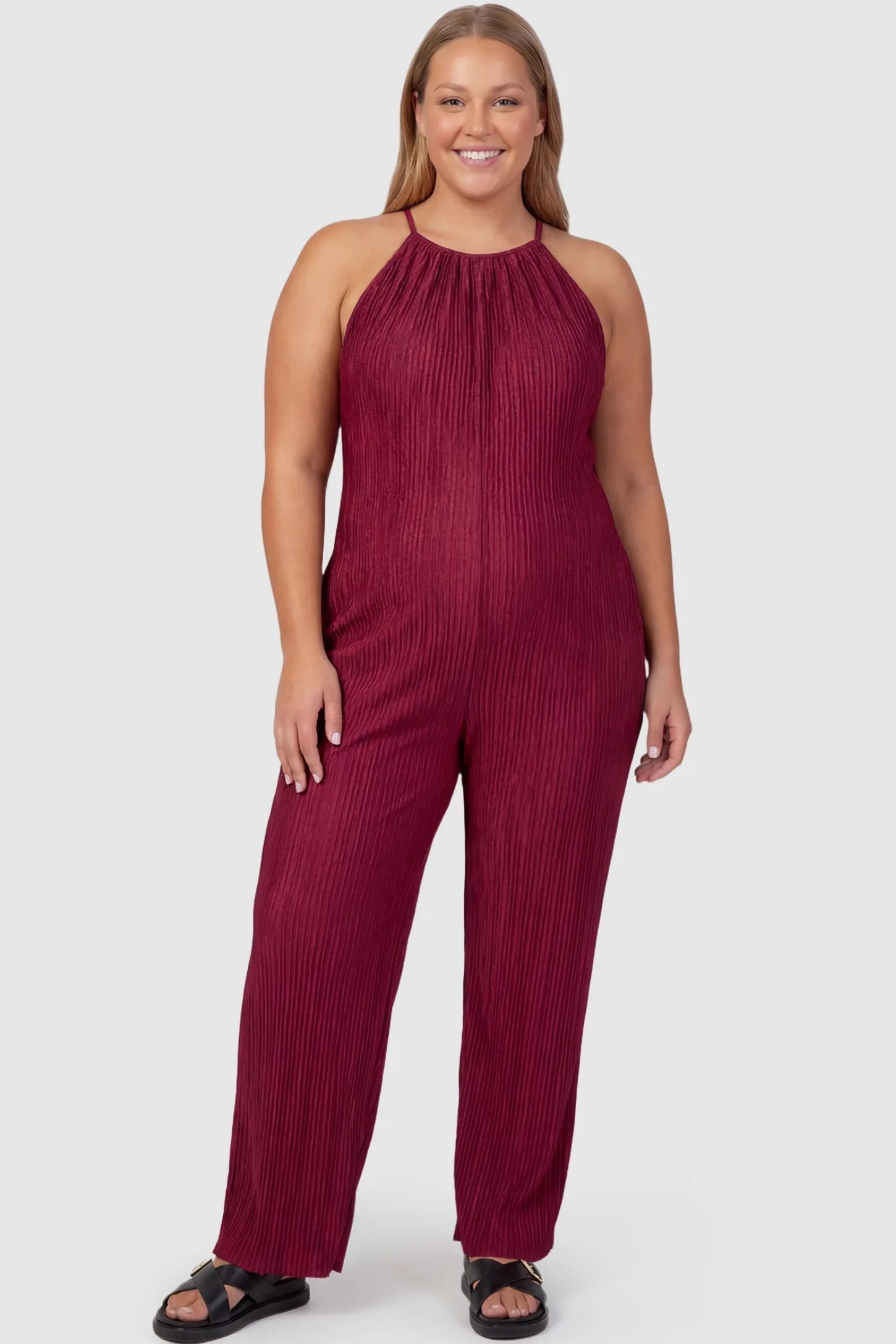 Halter Neck Wide Leg Pocketed Maternity Jumpsuit Halter Neck Wide Leg Pocketed Maternity Jumpsuit in Wine Red featuring a gathered halter neck and ribbed texture on a plus-size pregnant model, front view.