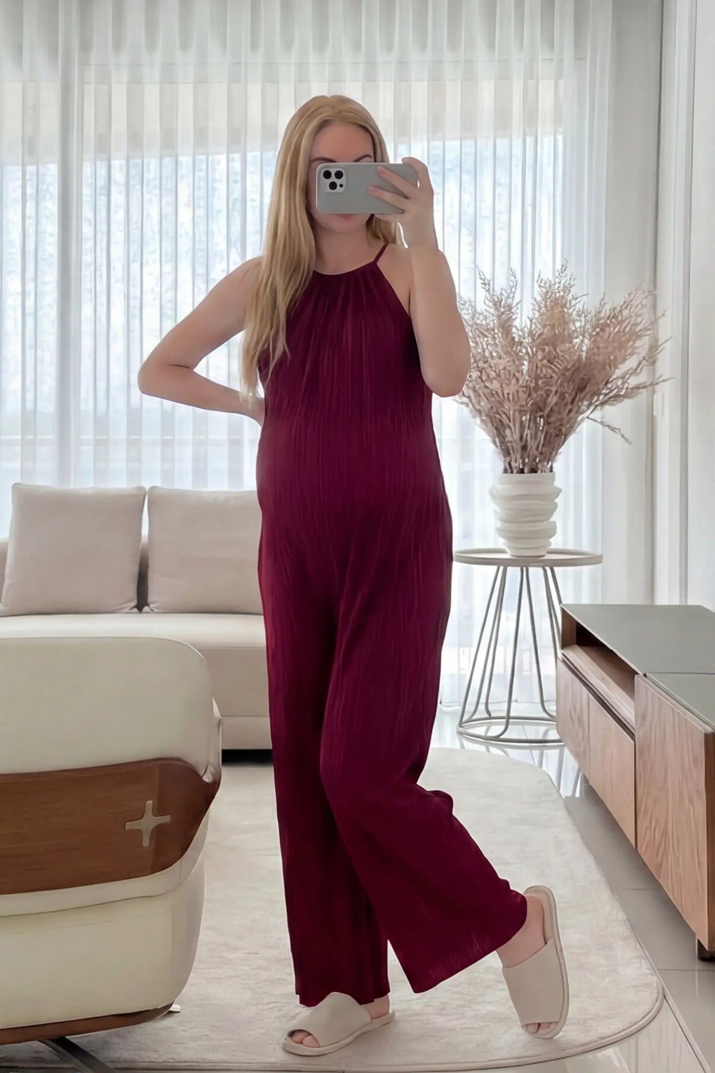 Halter Neck Wide Leg Pocketed Maternity Jumpsuit Halter Neck Wide Leg Pocketed Maternity Jumpsuit in Wine Red featuring a gathered halter neck and ribbed fabric on a pregnant model, UGC-style view.