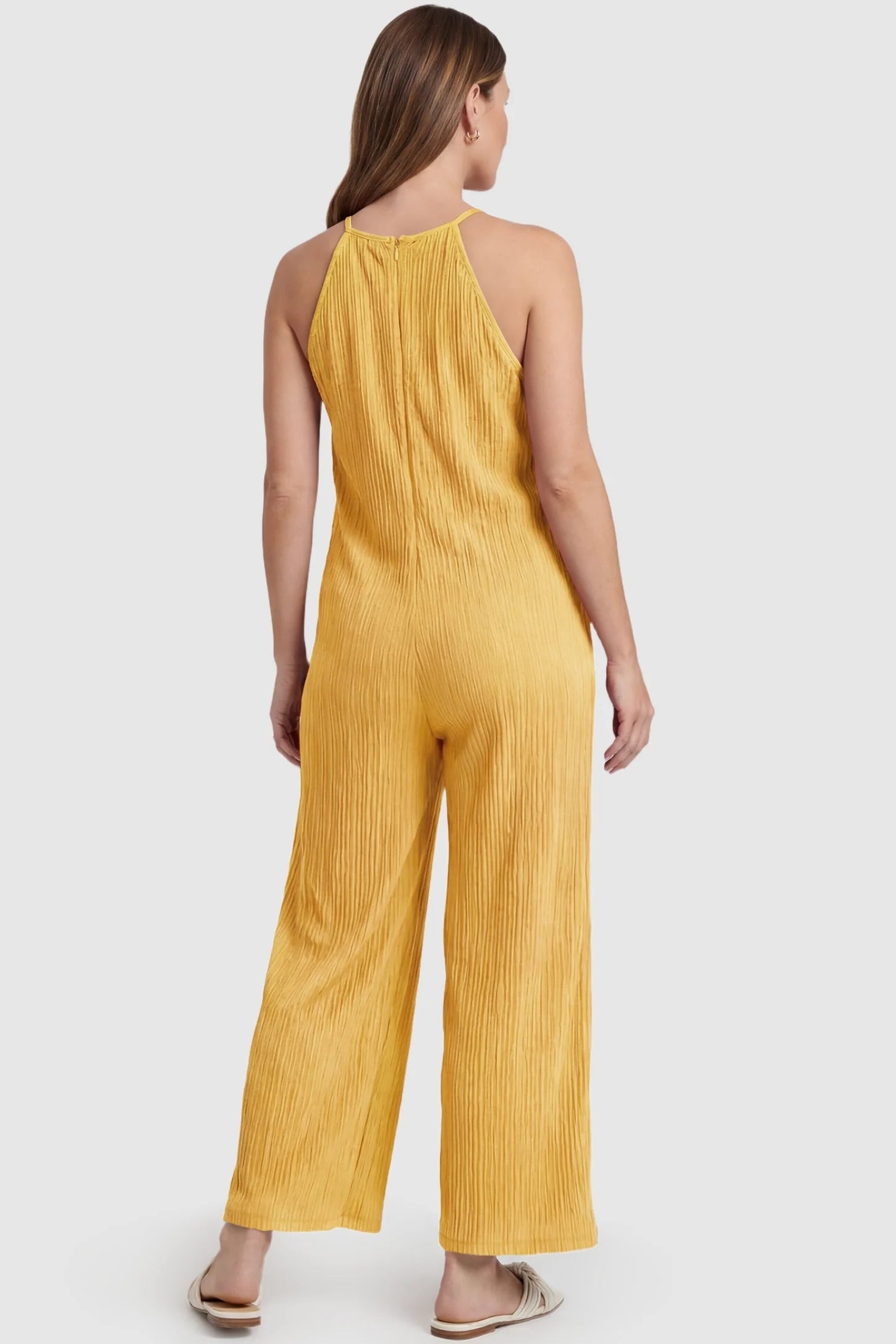 Halter Neck Wide Leg Pocketed Maternity Jumpsuit Halter Neck Wide Leg Pocketed Maternity Jumpsuit in Yellow featuring a halter neck and allover ribbing on a pregnant model, back view.