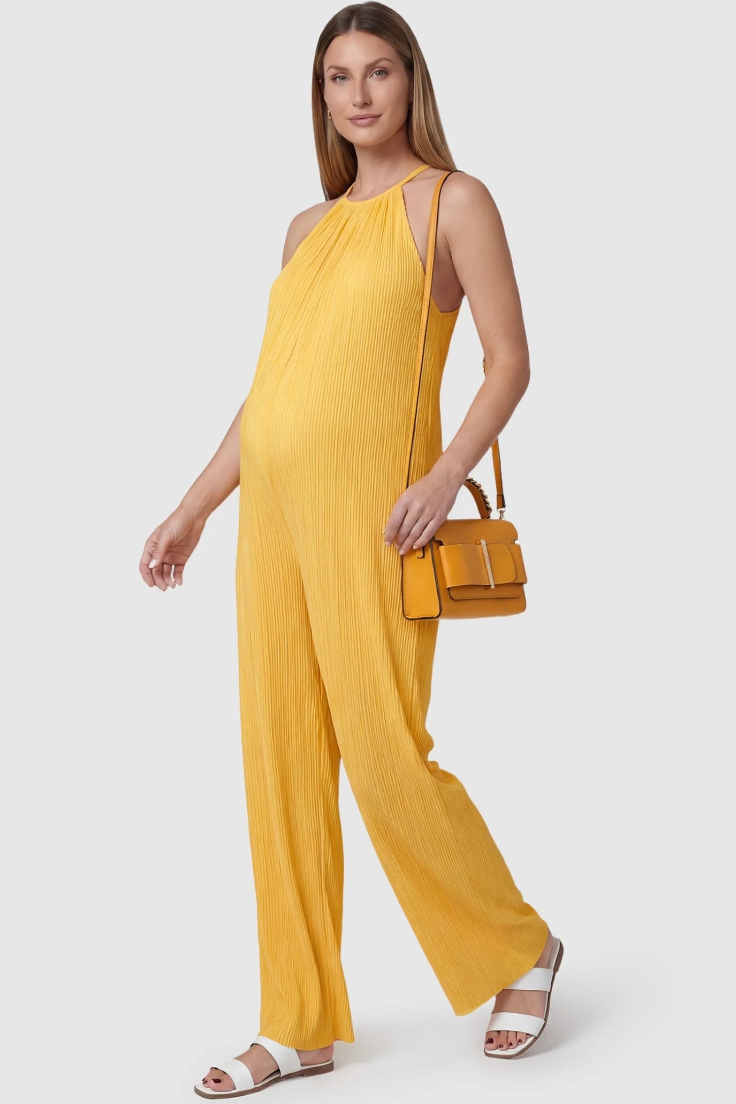 Halter Neck Wide Leg Pocketed Maternity Jumpsuit Halter Neck Wide Leg Pocketed Maternity Jumpsuit in Yellow featuring a gathered halter neck and ribbed texture on a pregnant model, styled lifestyle view.