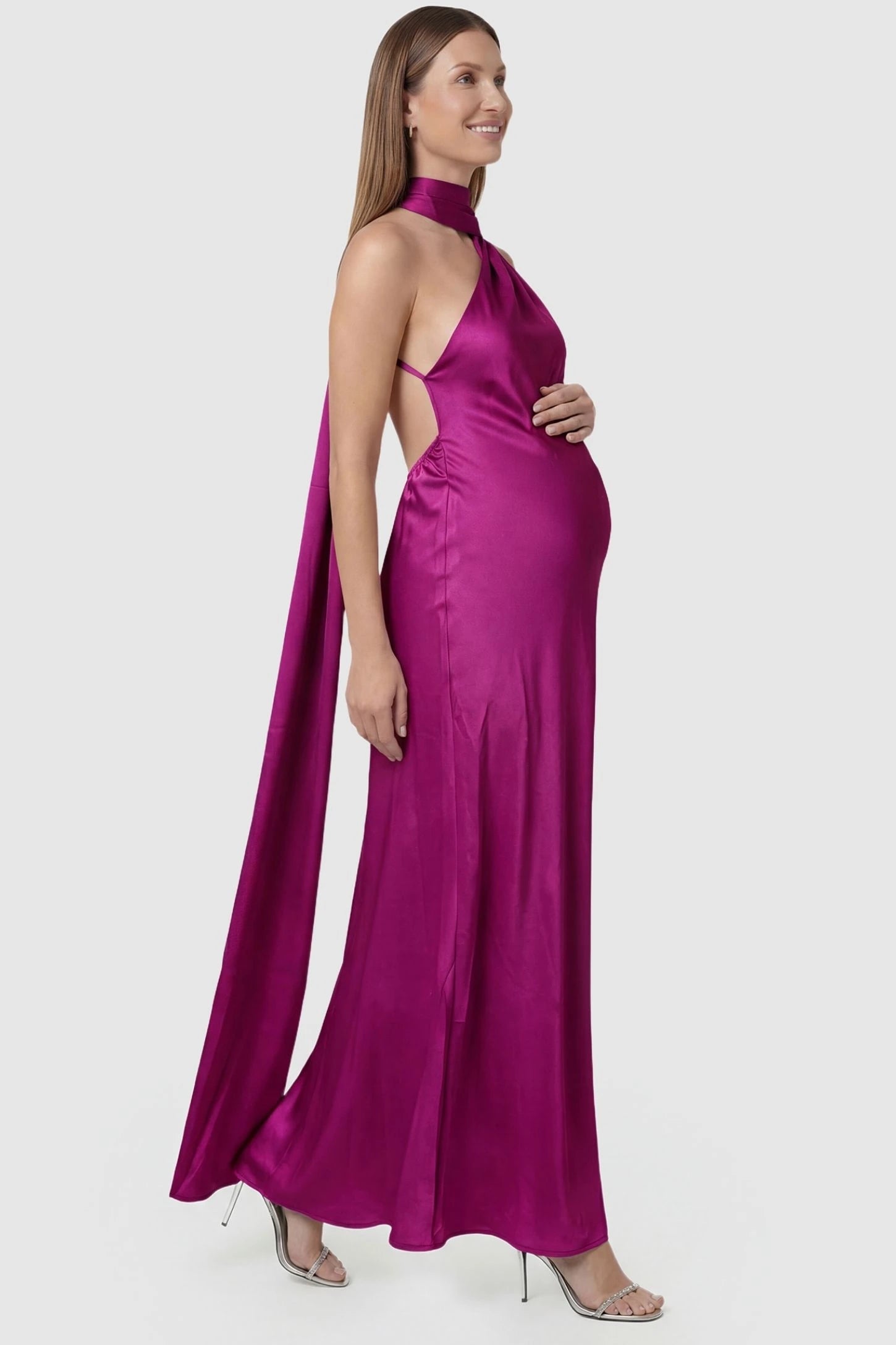 High-Shine Halter Sleeveless Maternity Maxi Dress High-Shine Halter Sleeveless Maternity Maxi Dress in Pink featuring a curve-hugging bump fit on a pregnant model, side view.