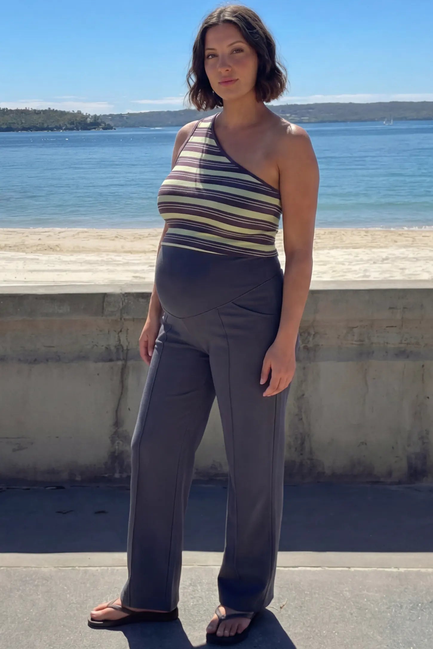 High Stretch Wide Leg Pocketed Maternity Pants High-Stretch Wide Leg Pocketed Maternity Pants in Dark Gray featuring a seamless over-the-bump panel and side pocket on a pregnant woman in outdoor setting, full body view.