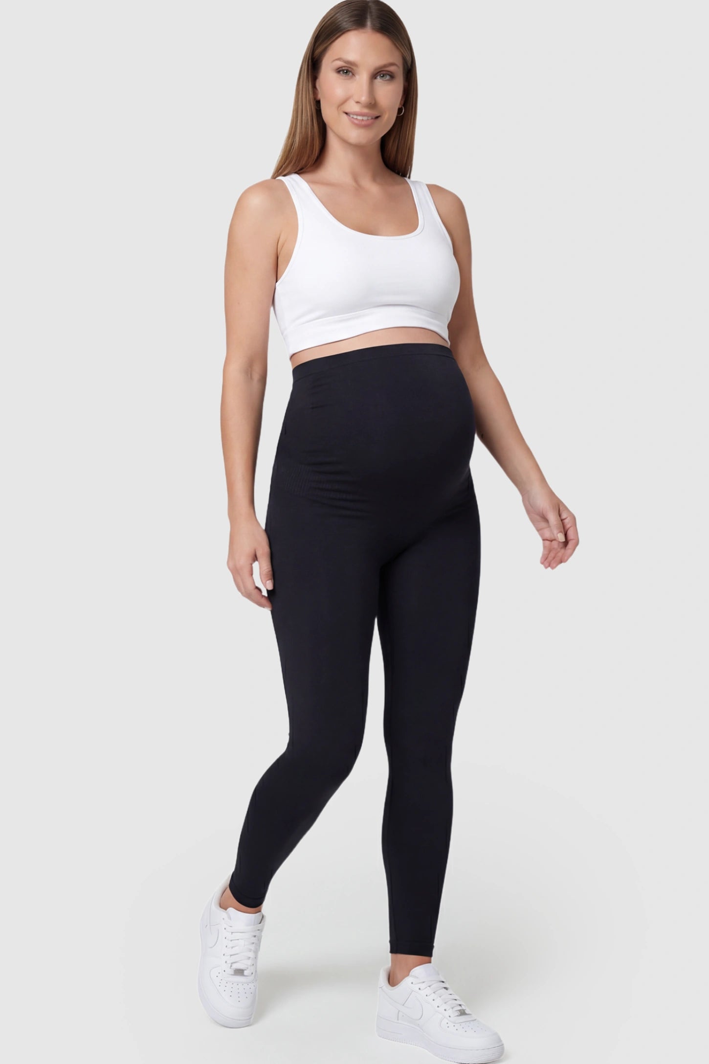 High Waisted Full Length Maternity Leggings High Waisted Full Length Maternity Leggings in Black featuring a seamless over-the-bump band on a pregnant model posing front.