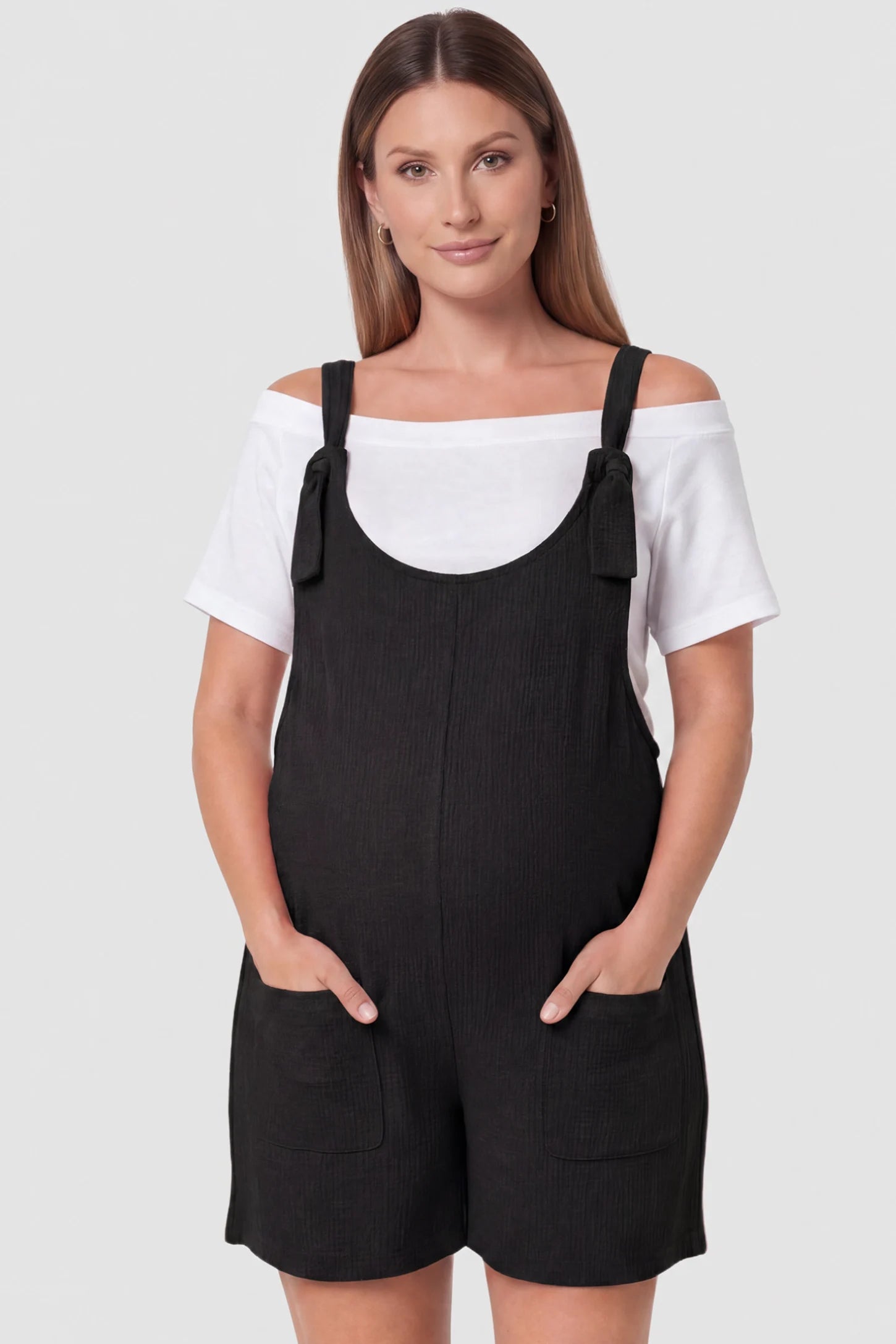 Knot Strap Front Pocket Maternity Romper Knot Strap Front Pocket Maternity Romper in Black featuring deep front pockets and a scoop neck on a pregnant model, front view.