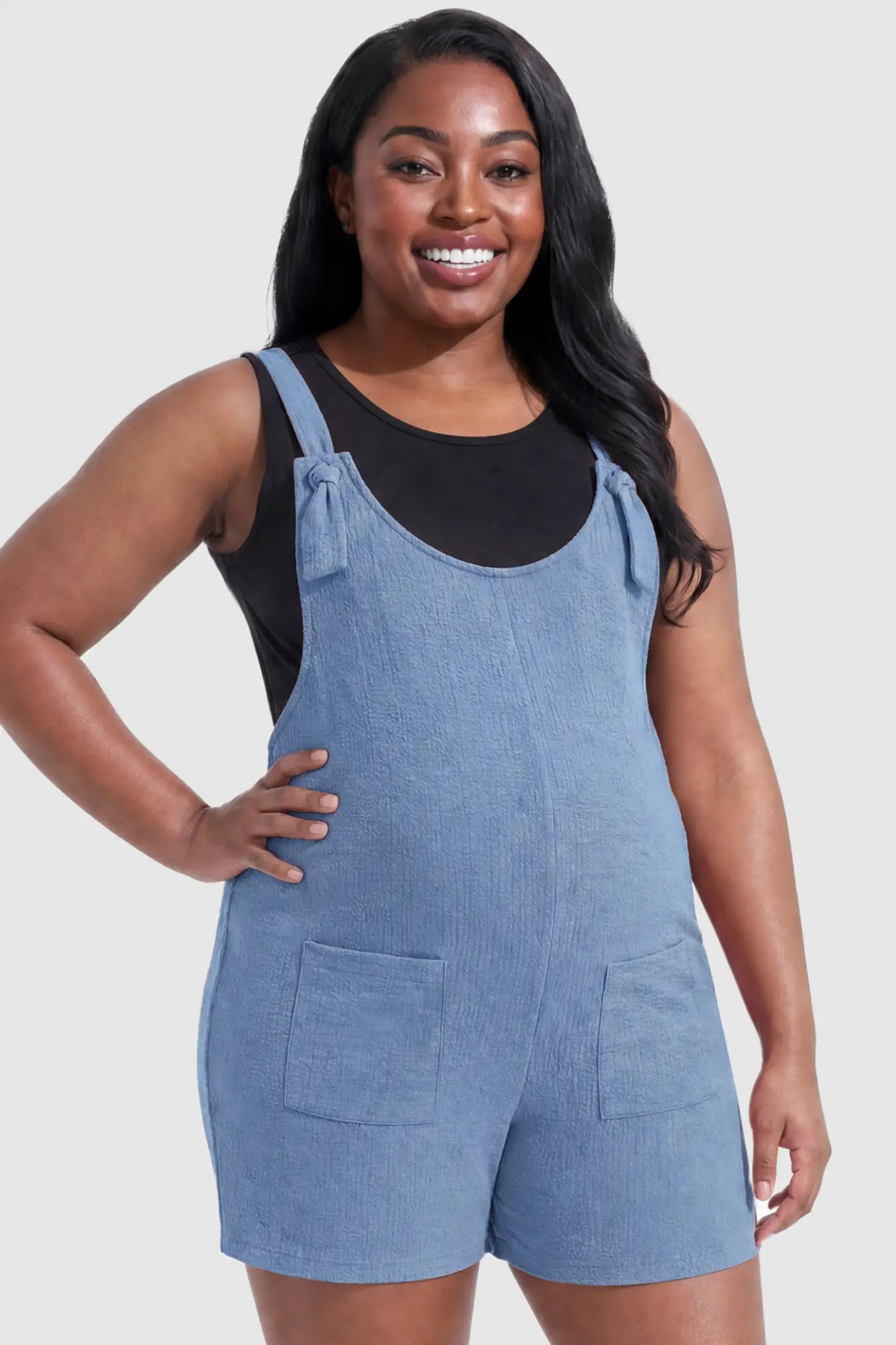 Knot Strap Front Pocket Maternity Romper Knot Strap Front Pocket Maternity Romper in Light Blue featuring deep front pockets and a scoop neck on a plus size pregnant model, front view.