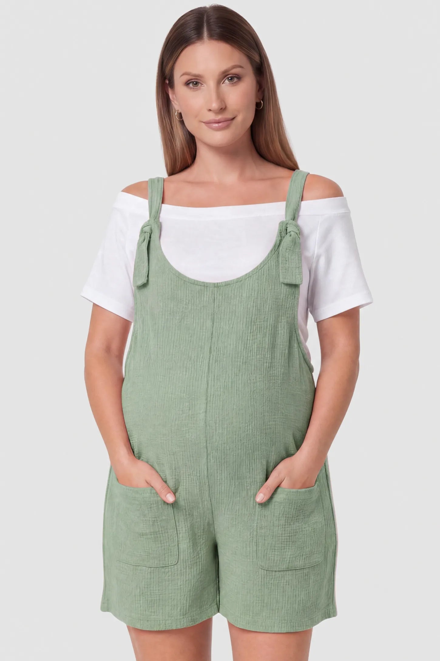 Knot Strap Front Pocket Maternity Romper Knot Strap Front Pocket Maternity Romper in Light Green featuring deep front pockets and a scoop neck on a pregnant model, front view.