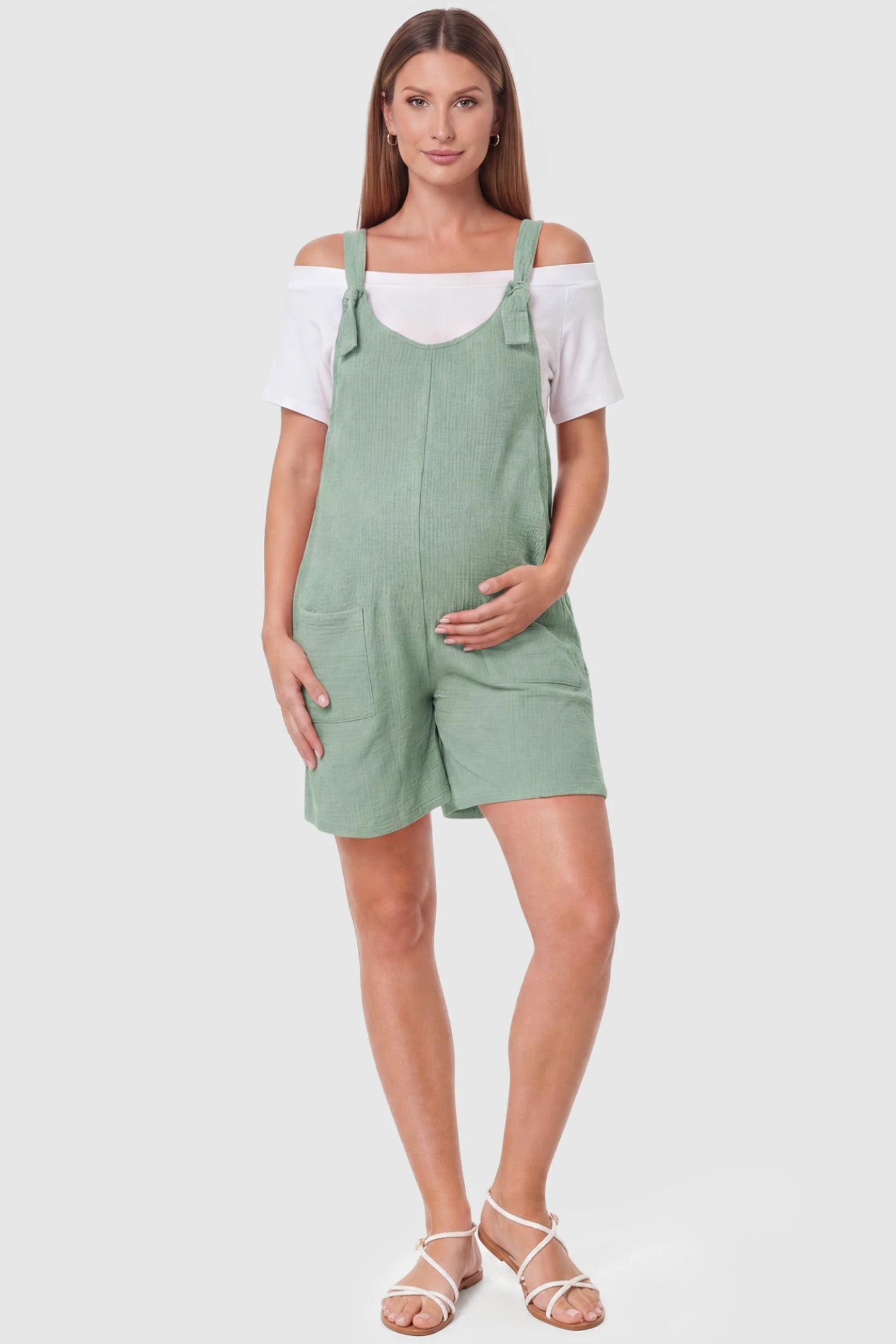 Knot Strap Front Pocket Maternity Romper Knot Strap Front Pocket Maternity Romper in Light Green featuring deep front pockets and a scoop neck on a pregnant model, full body view.