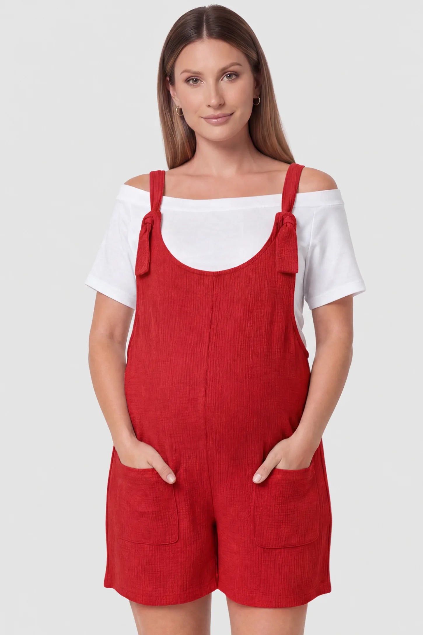 Knot Strap Front Pocket Maternity Romper Knot Strap Front Pocket Maternity Romper in Red featuring deep front pockets and a scoop neck on a pregnant model, front view.