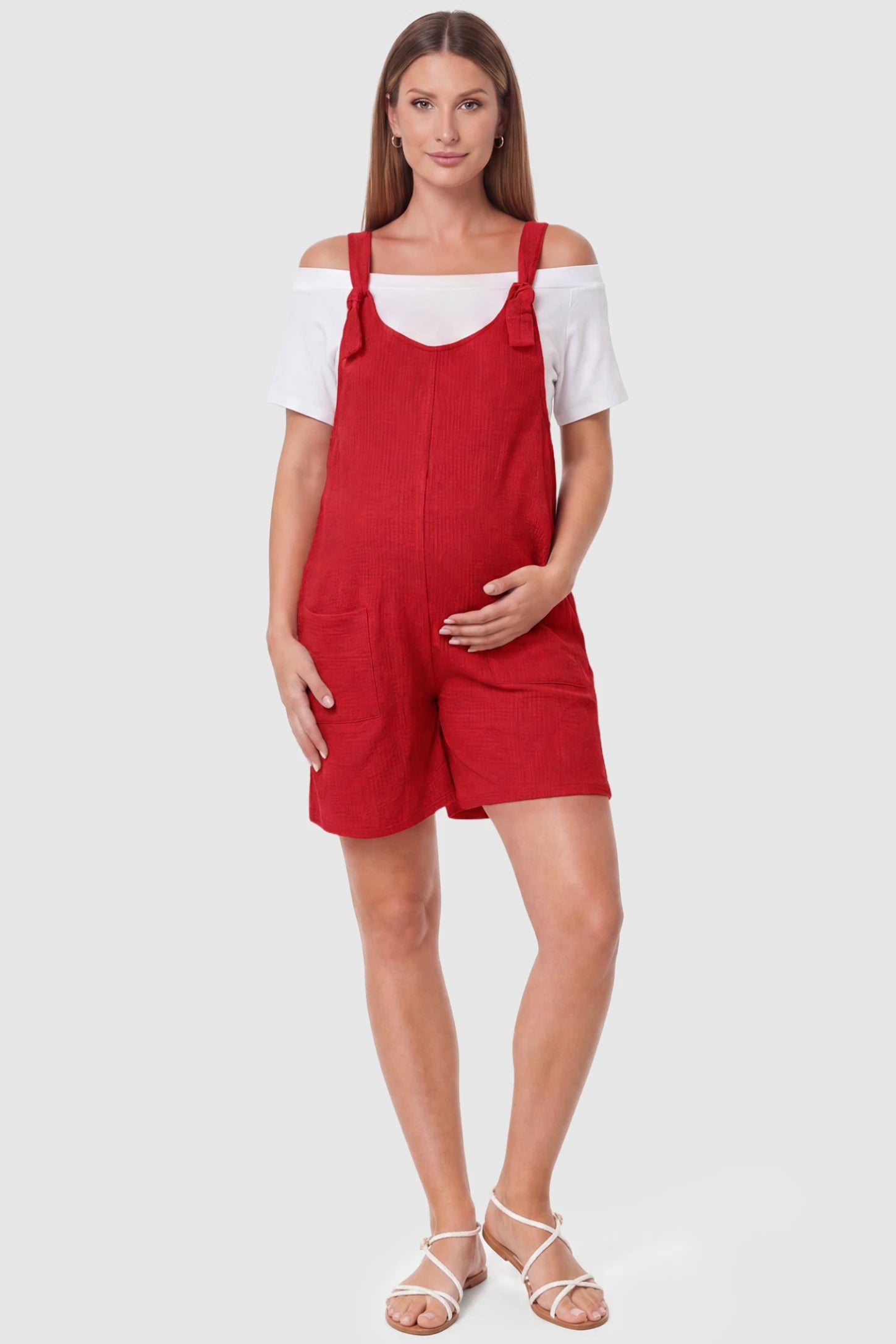 Knot Strap Front Pocket Maternity Romper Knot Strap Front Pocket Maternity Romper in Red featuring deep front pockets and a scoop neck on a pregnant model, full body view.