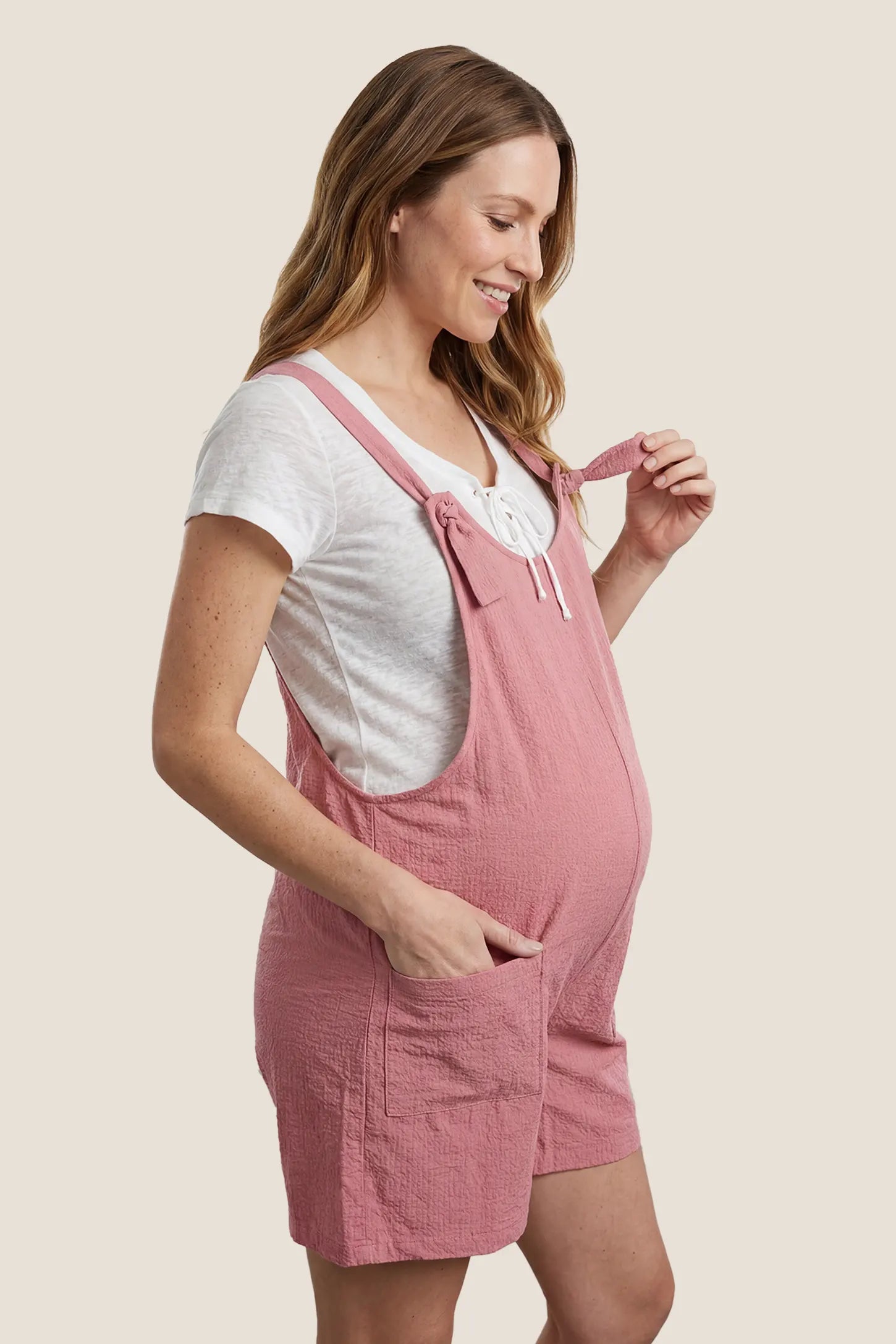 Knot Strap Front Pocket Maternity Romper Side view of the pink Knot Strap Front Pocket Maternity Romper designed for comfort throughout pregnancy.