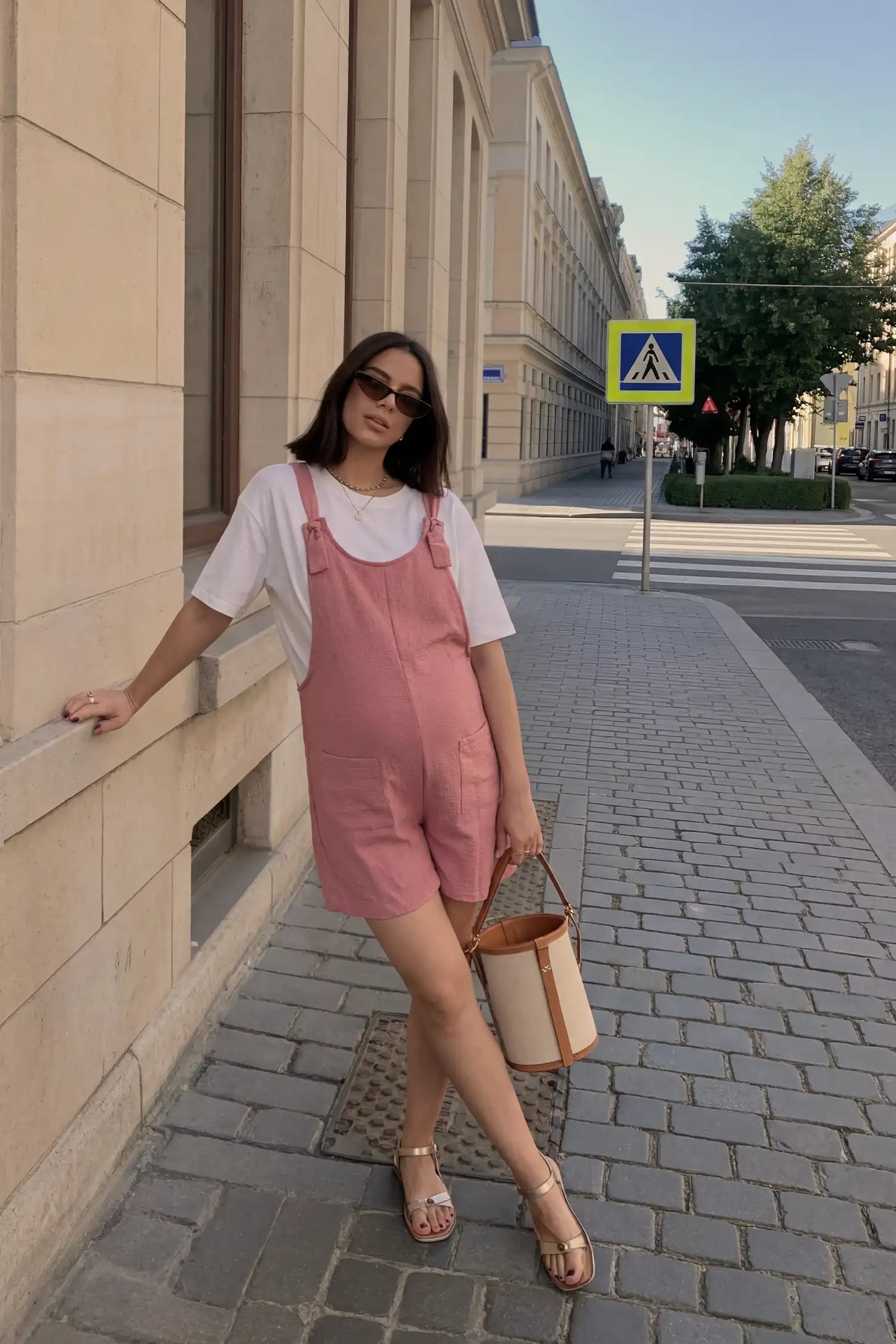 Knot Strap Front Pocket Maternity Romper Street lifestyle image of the pink Knot Strap Front Pocket Maternity Romper paired with a light tee for an effortless maternity look.