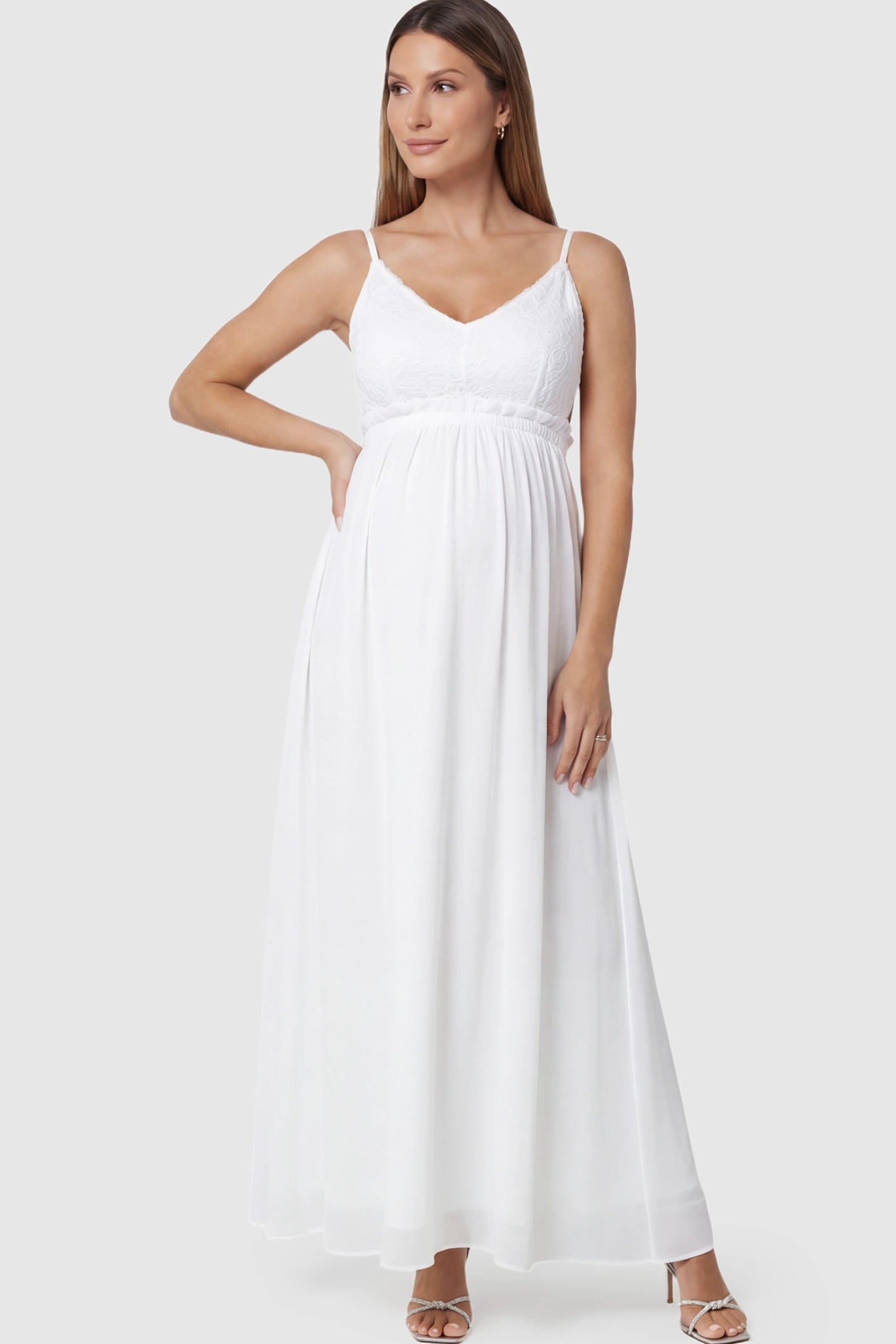 Lace Bodice V-Neck Maternity Maxi Dress in White featuring a floral lace overlay and spaghetti straps on a pregnant model posing front.