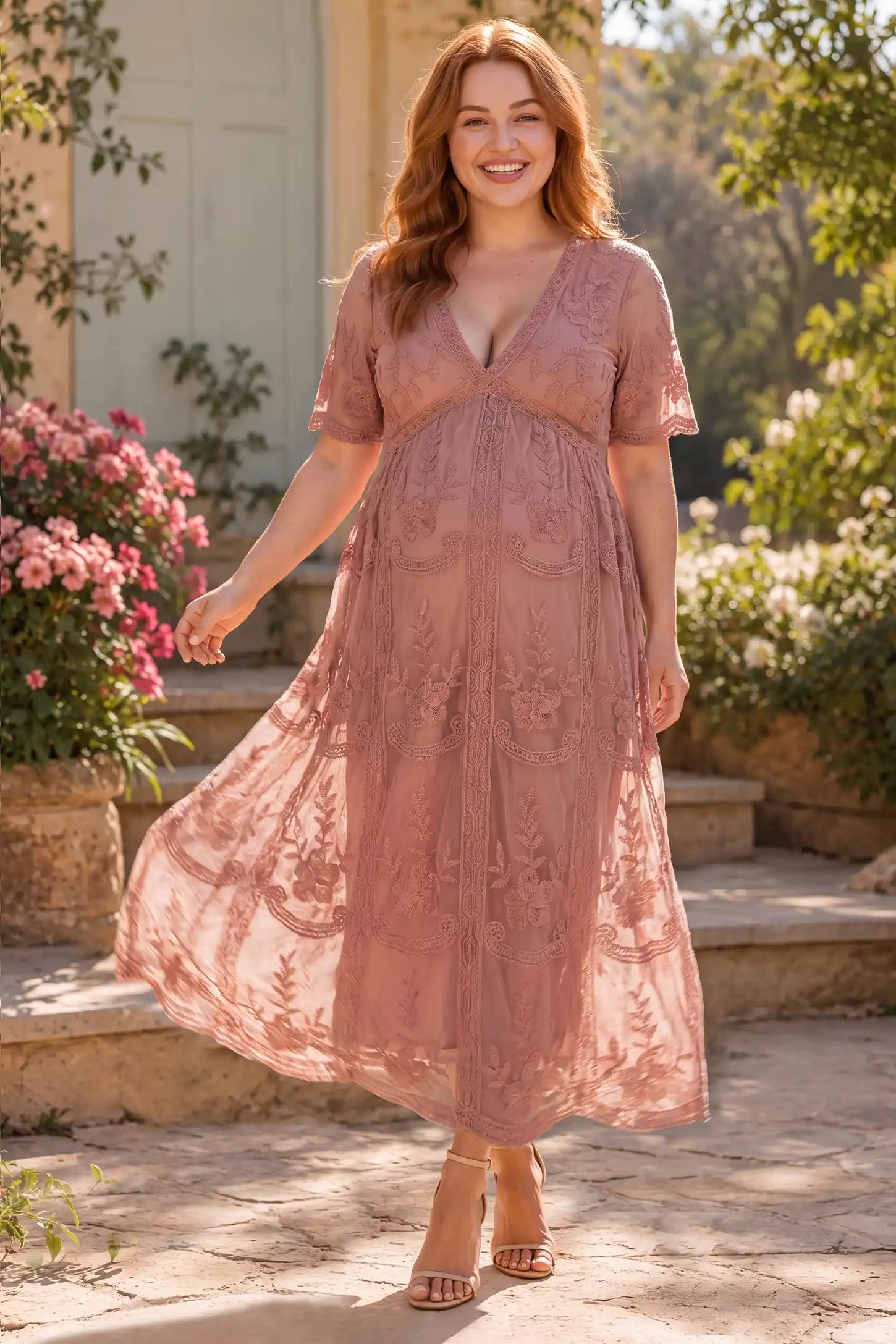 Lace Short Sheer Sleeve Maternity Maxi Dress Lace Short Sheer Sleeve Maternity Maxi Dress in Pink with a flattering lace bodcie and sheer sleeves, lifestyle view on a plus-size model.