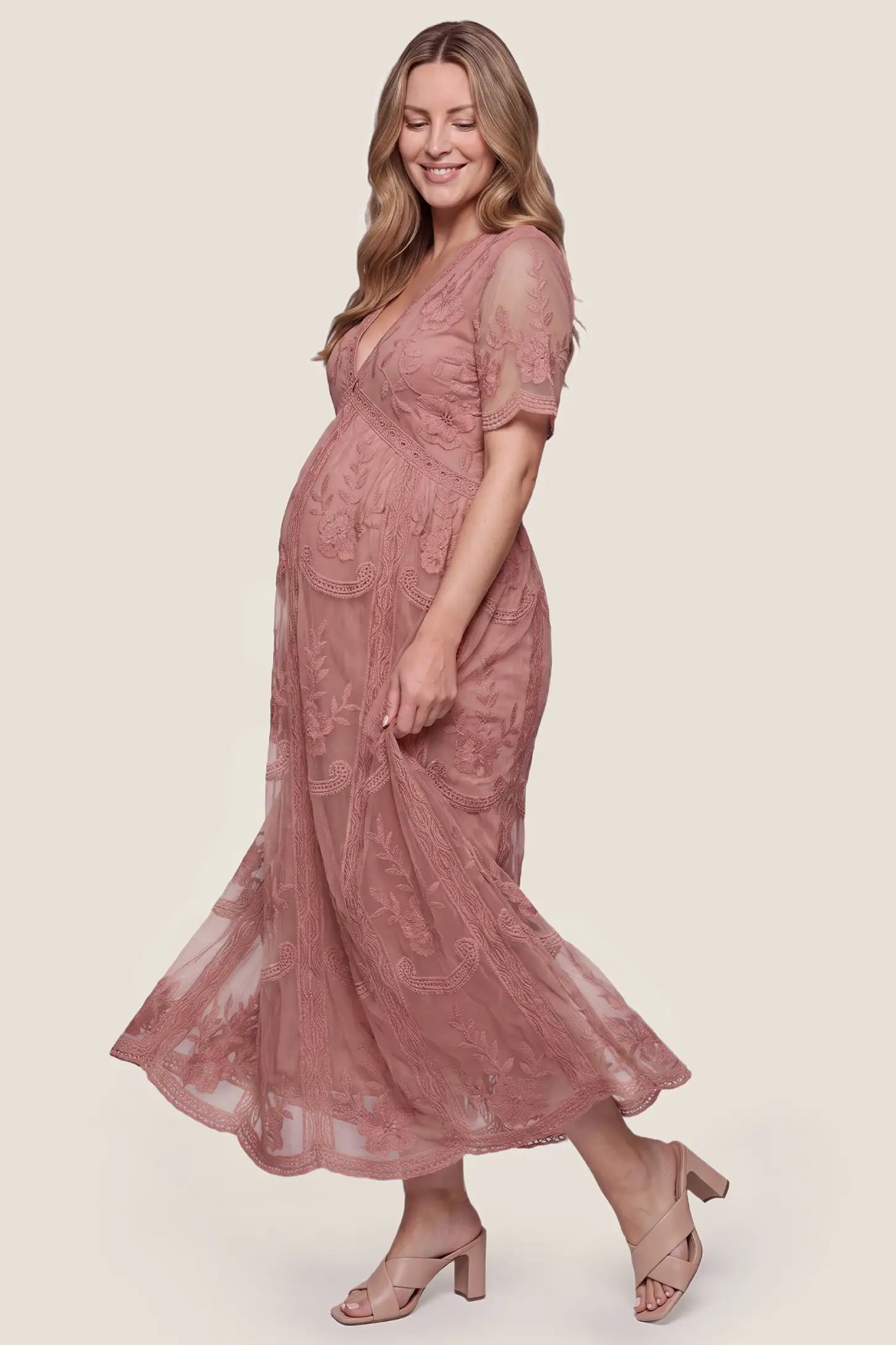 Lace Short Sheer Sleeve Maternity Maxi Dress Lace Short Sheer Sleeve Maternity Maxi Dress in Pink with an empire waist and flowing skirt, side view on a pregnant model.