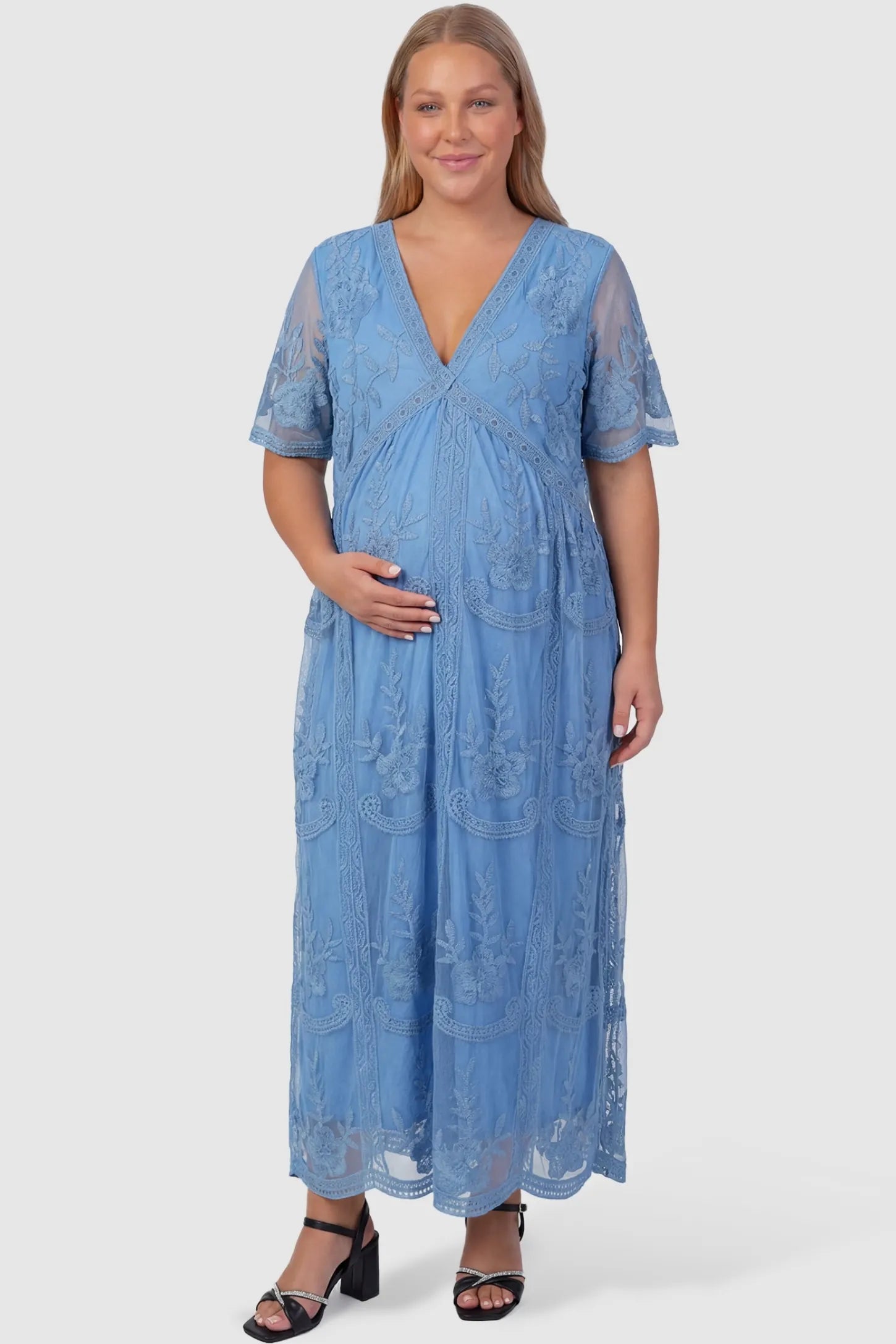 Lace Short Sheer Sleeve Maternity Maxi Dress Lace Short Sheer Sleeve Maternity Maxi Dress in blue featuring sheer mesh sleeves and v-neckline on a non-plus-size pregnant model, front view.
