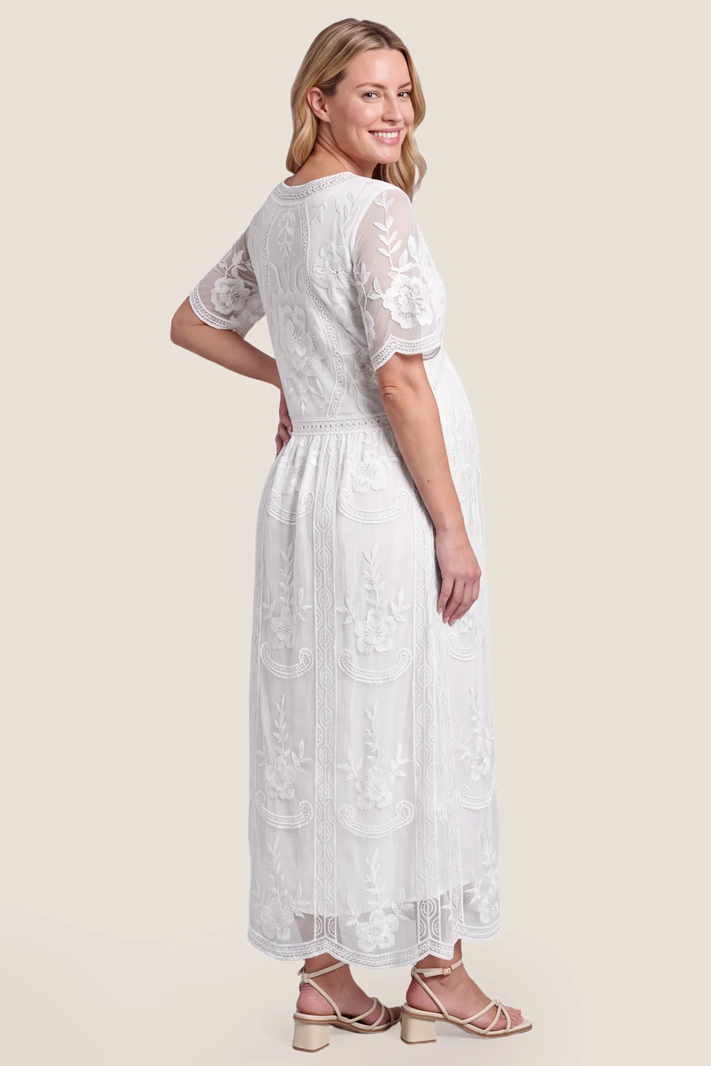 Lace Short Sheer Sleeve Maternity Maxi Dress Lace Short Sheer Sleeve Maternity Maxi Dress in white featuring a scalloped lace hem on a pregnant model, back view.