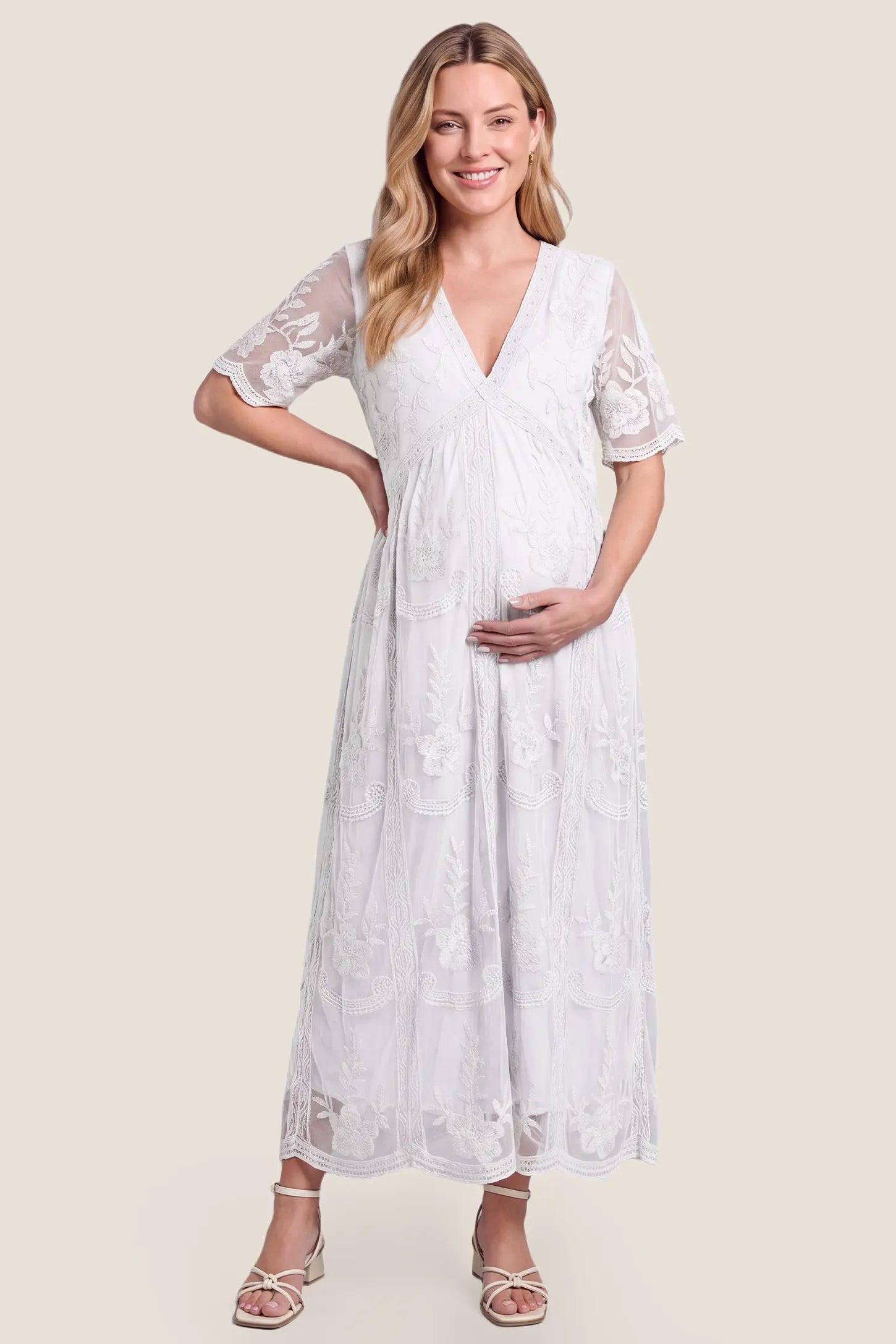 Lace Short Sheer Sleeve Maternity Maxi Dress Lace Short Sheer Sleeve Maternity Maxi Dress in white featuring embroidered sheer sleeves on a pregnant model, front view.