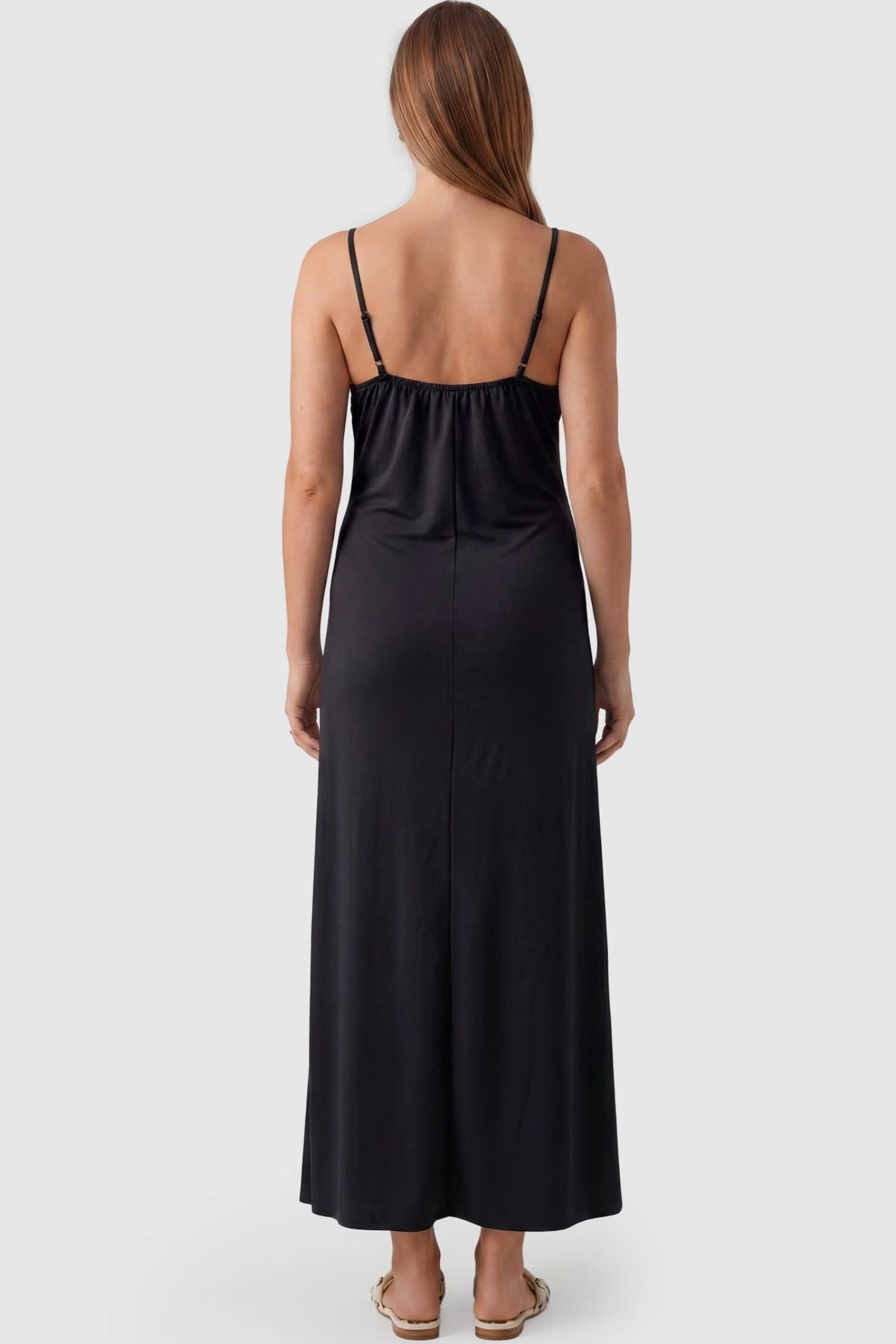 Lace-Trim Maternity Slip Dress Lace-Trim Maternity Slip Dress in Black featuring thin spaghetti straps on a pregnant model, back view.