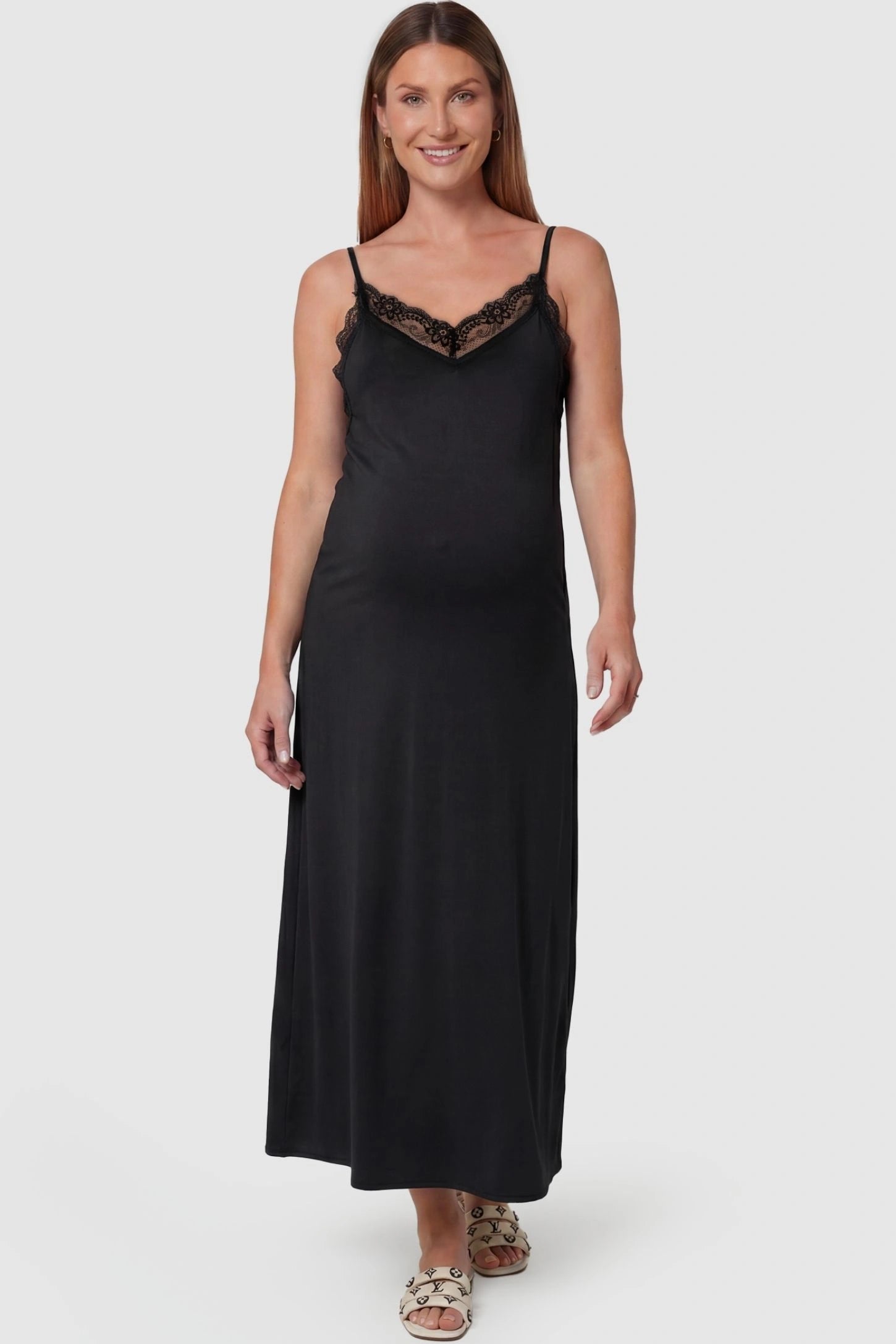 Lace-Trim Maternity Slip Dress Lace-Trim Maternity Slip Dress in Black featuring delicate spaghetti straps on a pregnant model, front view.