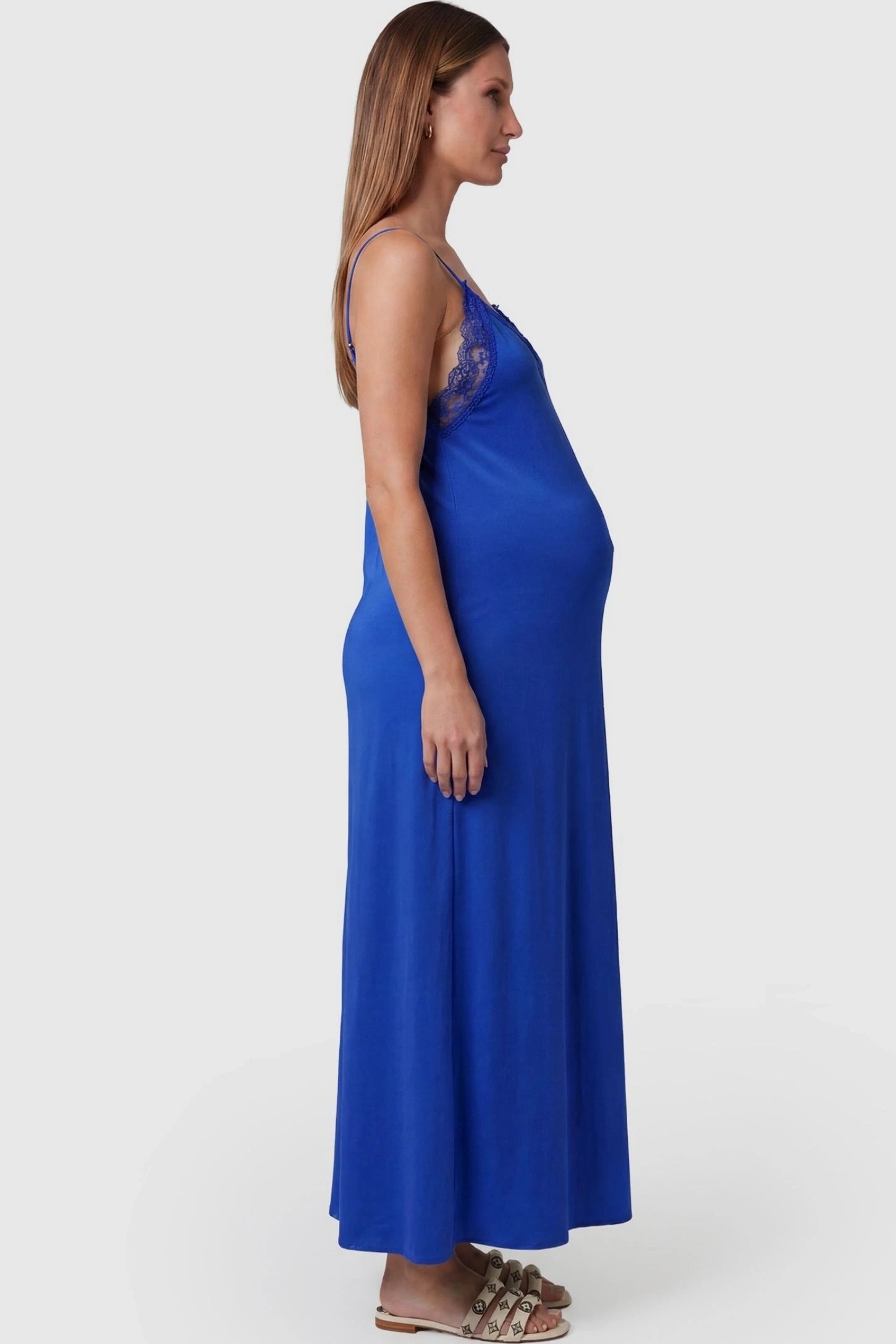 Lace-Trim Maternity Slip Dress Lace-Trim Maternity Slip Dress in Blue featuring dainty spaghetti straps on a pregnant model, side view.