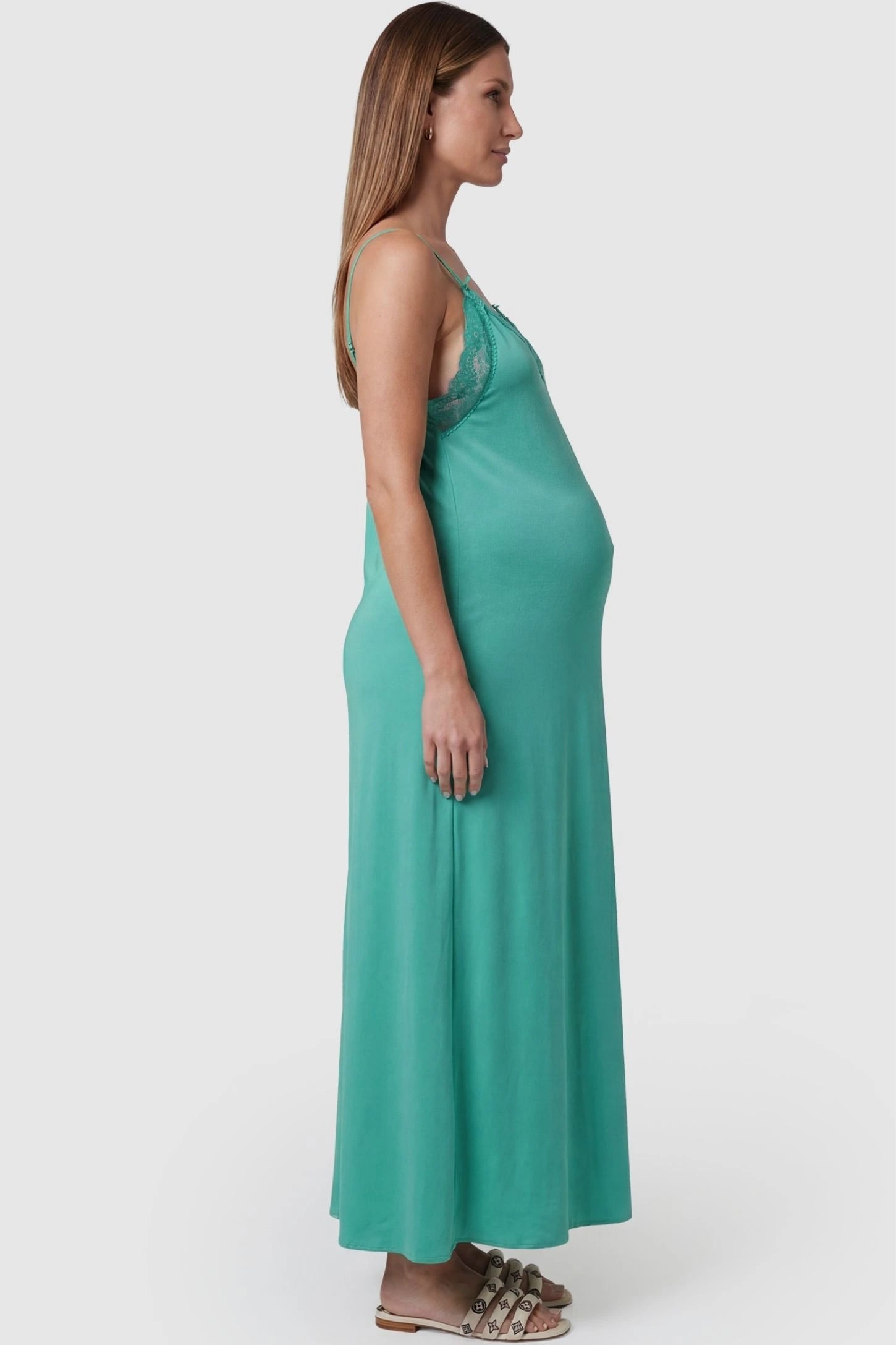 Lace-Trim Maternity Slip Dress Lace-Trim Maternity Slip Dress in Green featuring dainty spaghetti straps on a pregnant model, side view.