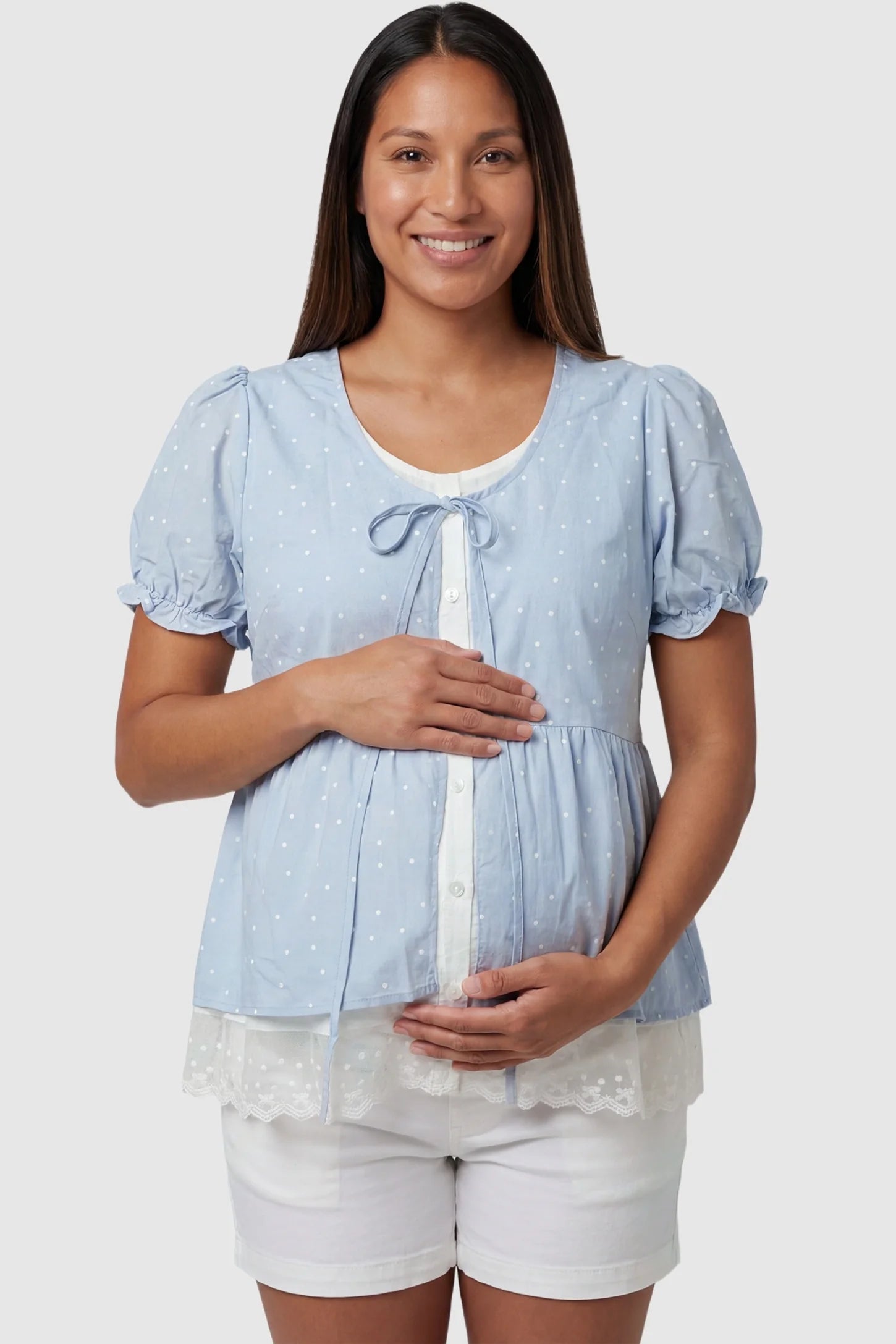 Laced Polka Dot Babydoll Maternity Blouse Laced Polka Dot Babydoll Maternity Blouse in Blue featuring a tie bow neckline on a non-pregnant model, UGC front view.