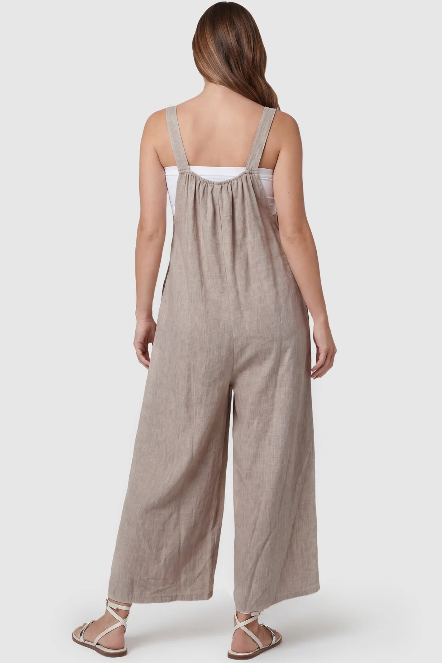 Loose Fit Wide Leg Sleeveless Maternity Jumpsuit Loose Fit Wide Leg Sleeveless Maternity Jumpsuit in Light Brown featuring a gathered back neckline and wide leg silhouette on a pregnant model, back view.