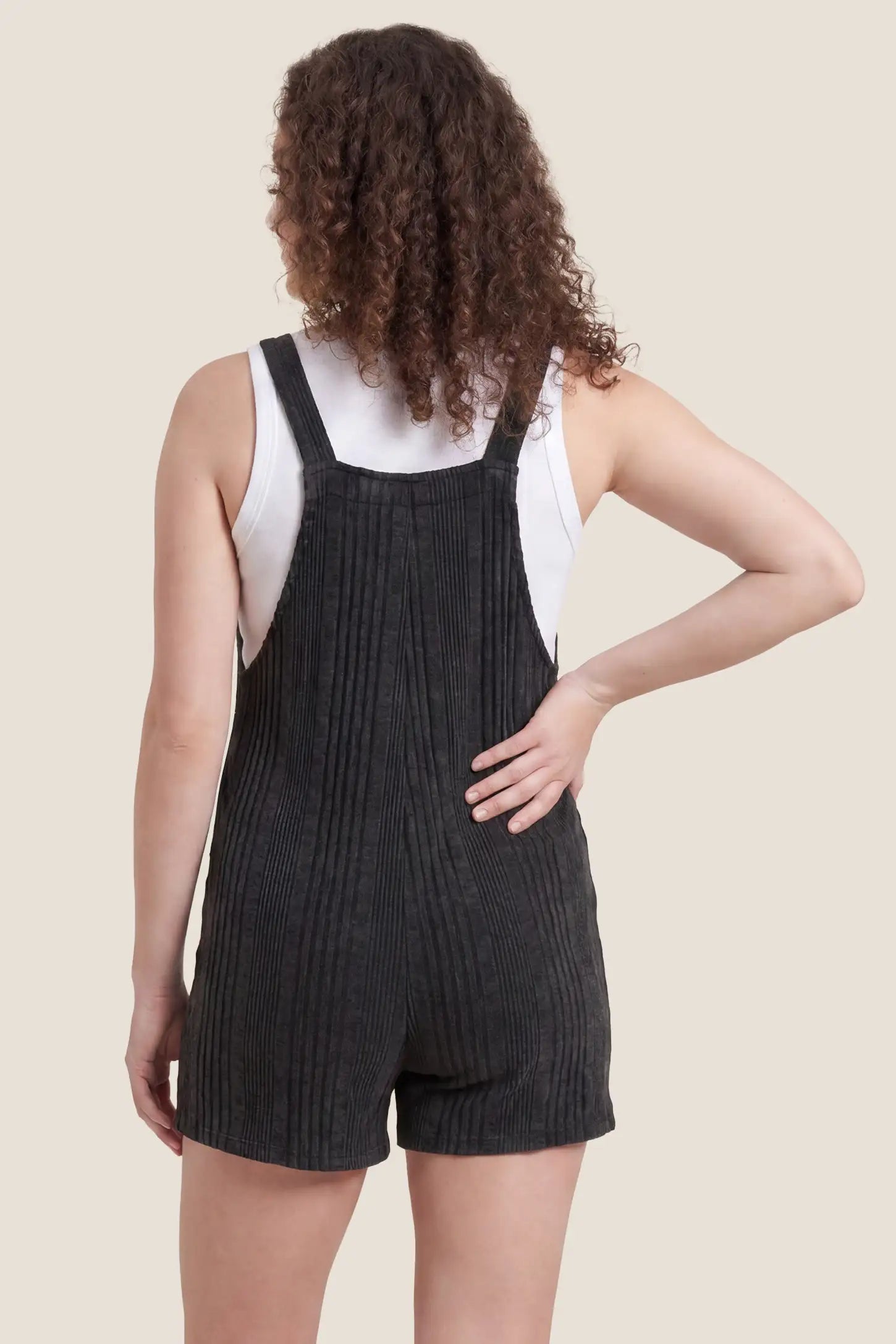 Ribbed Pocket Knit Maternity Romper Ribbed Pocket Knit Romper in Black featuring an all-over ribbed pattern on a pregnant model, back view.
