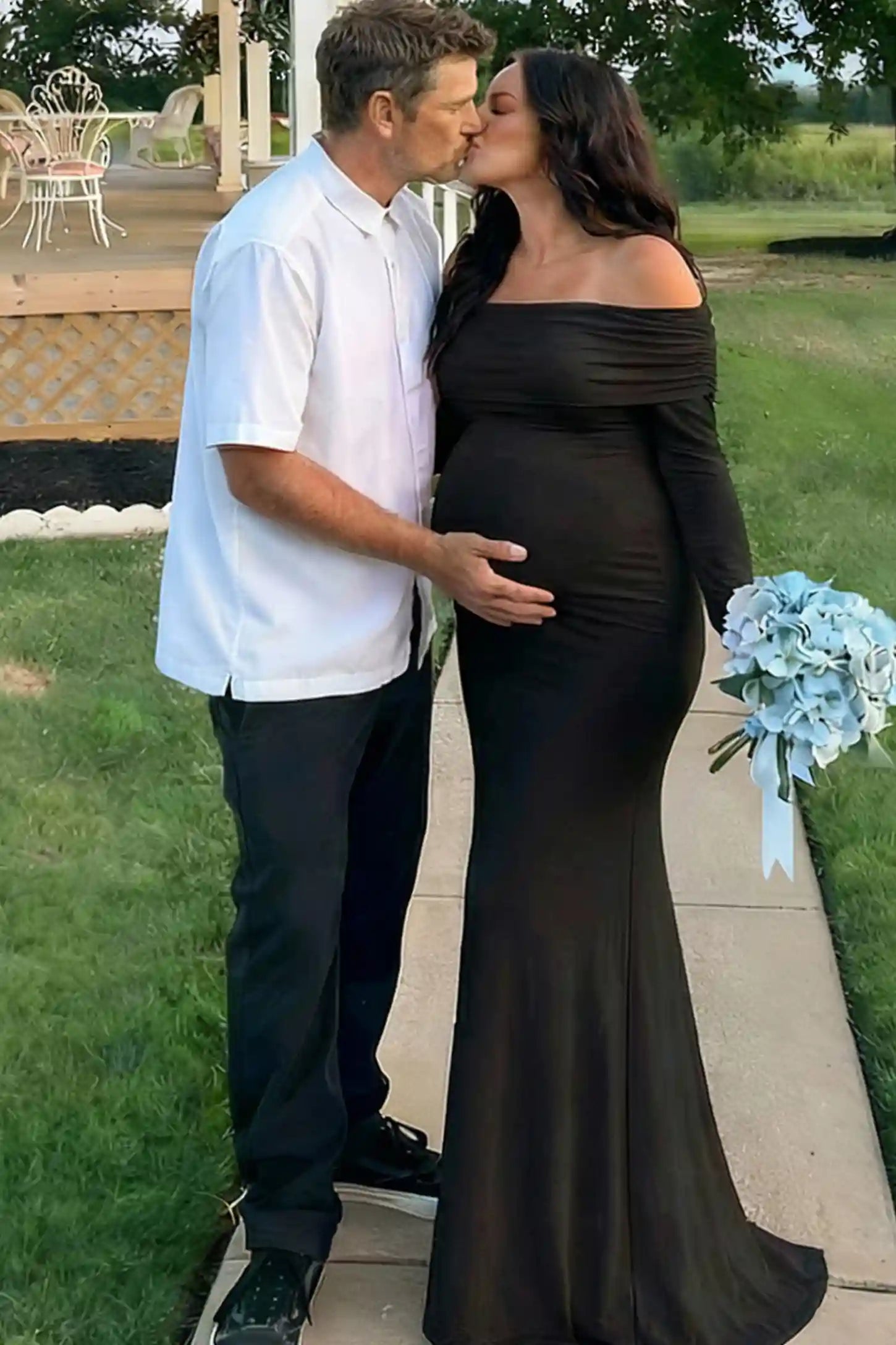 Solid Off Shoulder Bodycon Maternity Maxi Dress Off Shoulder Bodycon Maternity Maxi Dress in Black featuring a smooth stretch finish on a pregnant model posing with a partner.