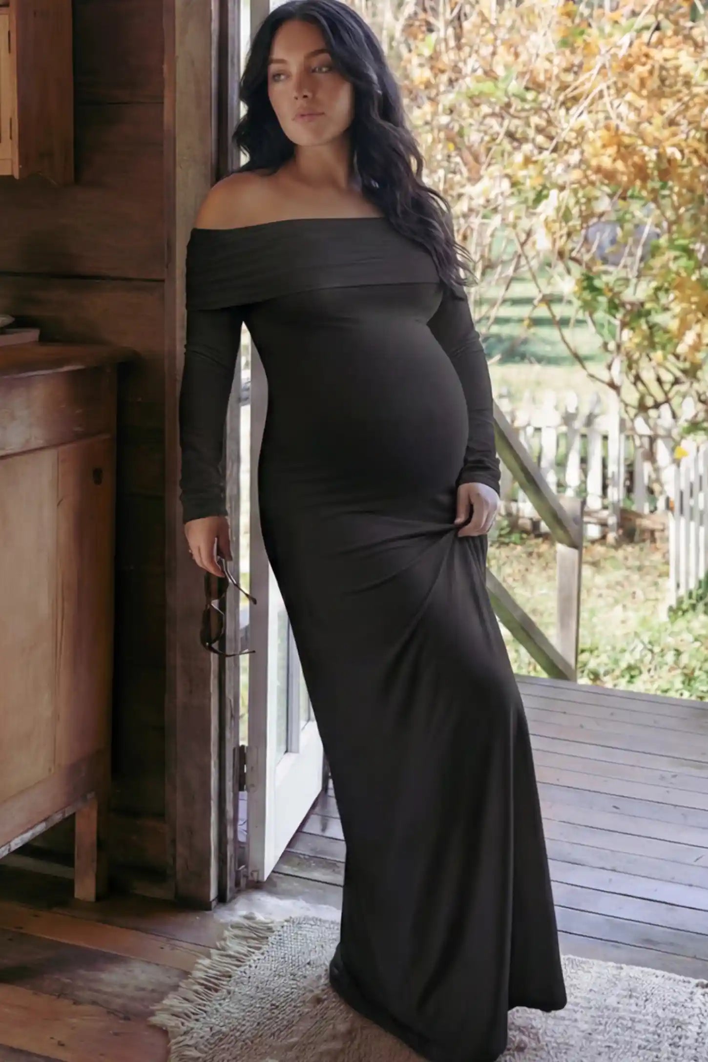 Solid Off Shoulder Bodycon Maternity Maxi Dress Off Shoulder Bodycon Maternity Maxi Dress in Black featuring a smooth stretch finish on a pregnant woman in a home setting.