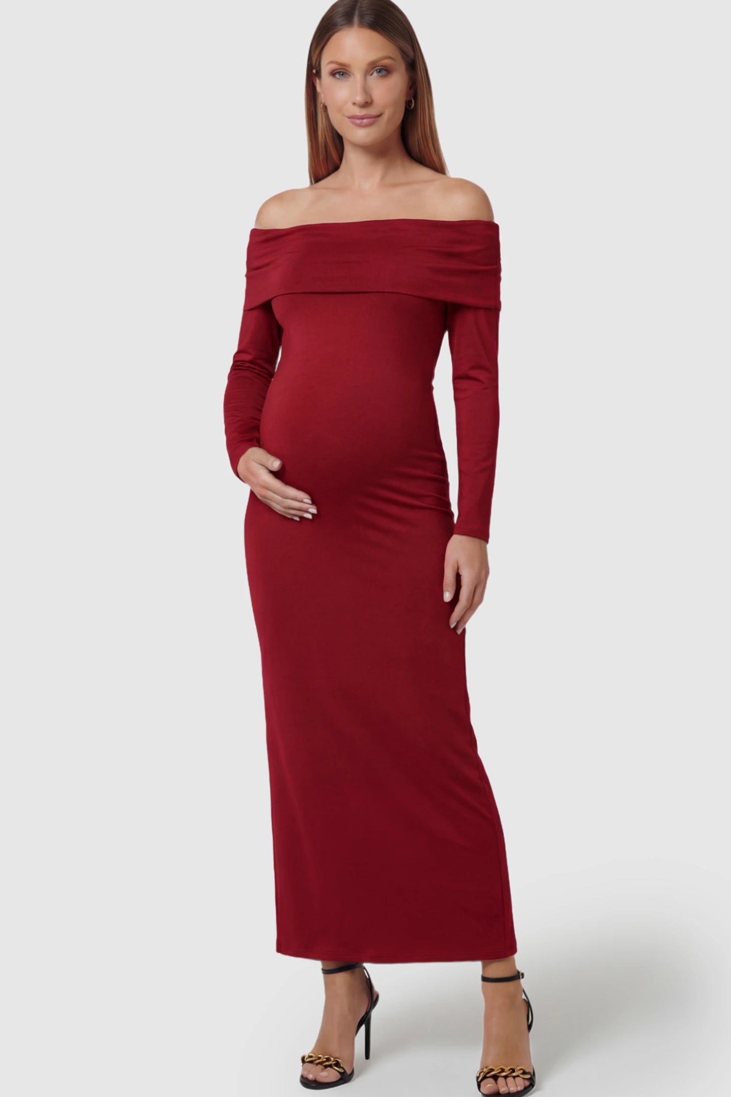 Solid Off Shoulder Bodycon Maternity Maxi Dress Off Shoulder Bodycon Maternity Maxi Dress in red featuring a smooth stretch finish on a pregnant model showing front.