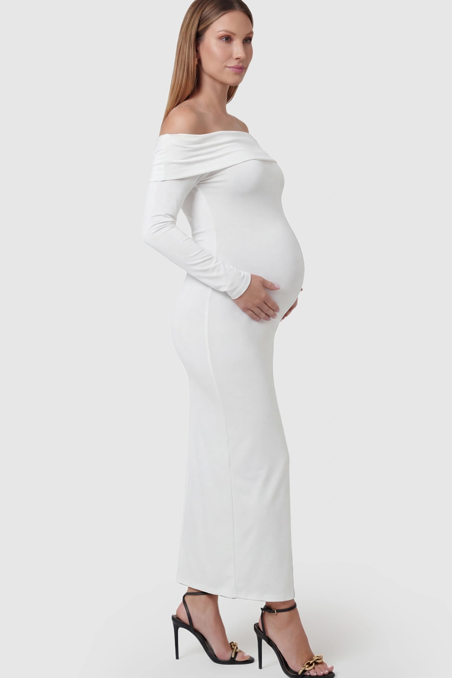 Solid Off Shoulder Bodycon Maternity Maxi Dress Off Shoulder Bodycon Maternity Maxi Dress in white featuring a smooth stretch finish on a pregnant model showing side.