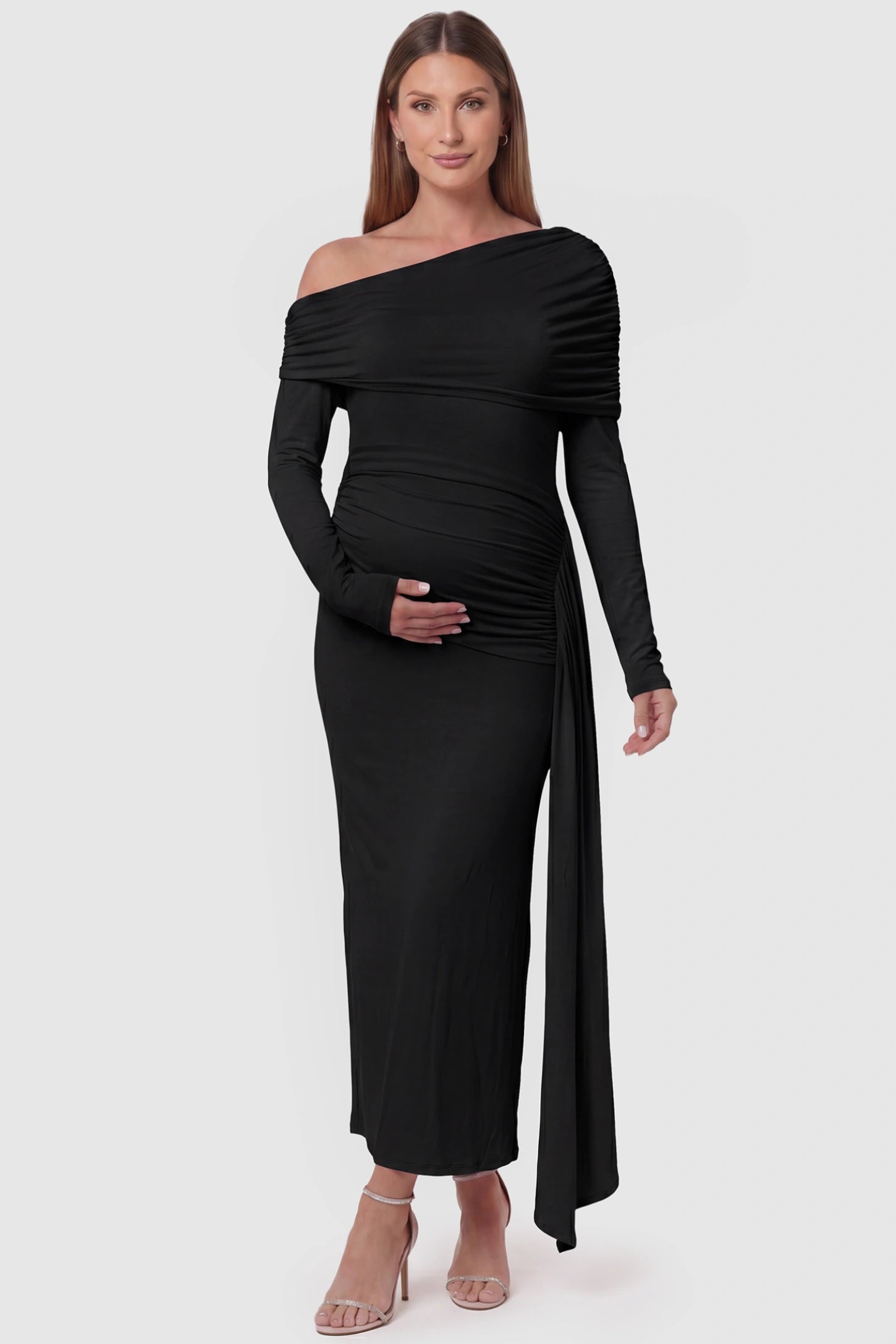 Off Shoulder Draped Wrap Bodycon Maternity Maxi Dress Off Shoulder Draped Wrap Bodycon Maternity Maxi Dress in Black featuring side ruching and long sleeves on a pregnant model, front view.