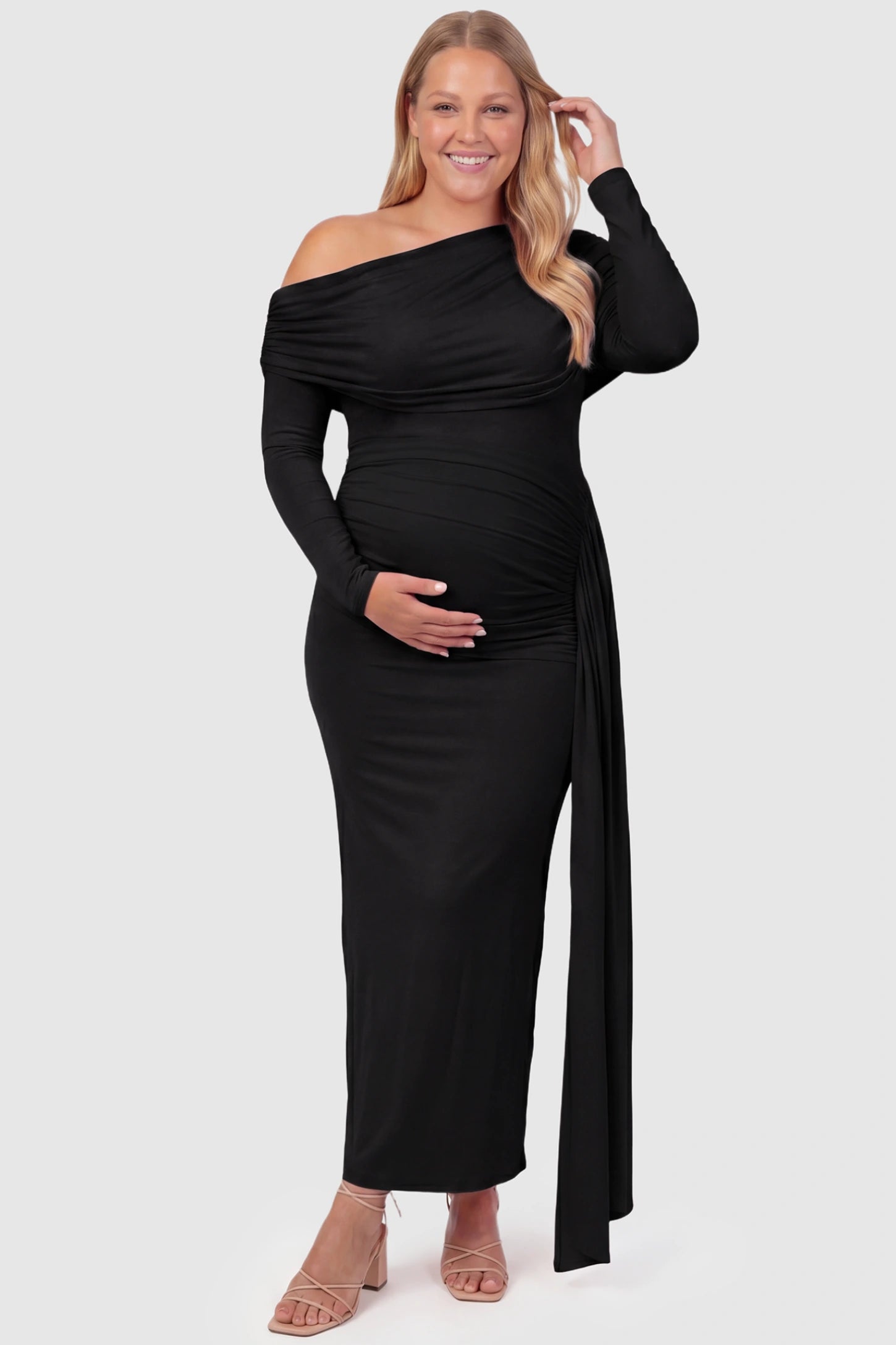 Off Shoulder Draped Wrap Bodycon Maternity Maxi Dress Off Shoulder Draped Wrap Bodycon Maternity Maxi Dress in Black featuring side ruching and long sleeves on a plus size pregnant model, front view.