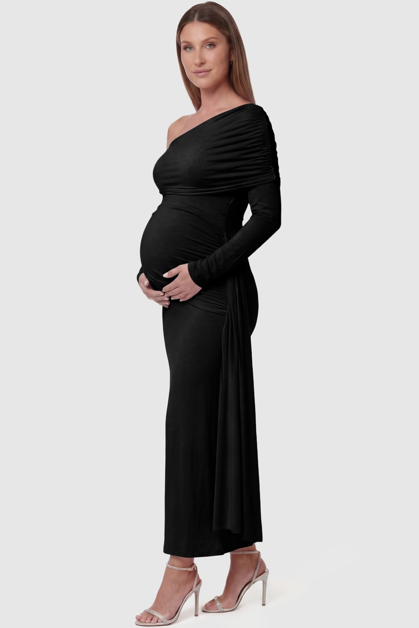 Off Shoulder Draped Wrap Bodycon Maternity Maxi Dress Off Shoulder Draped Wrap Bodycon Maternity Maxi Dress in Black featuring side ruching and long sleeves on a pregnant model side view.