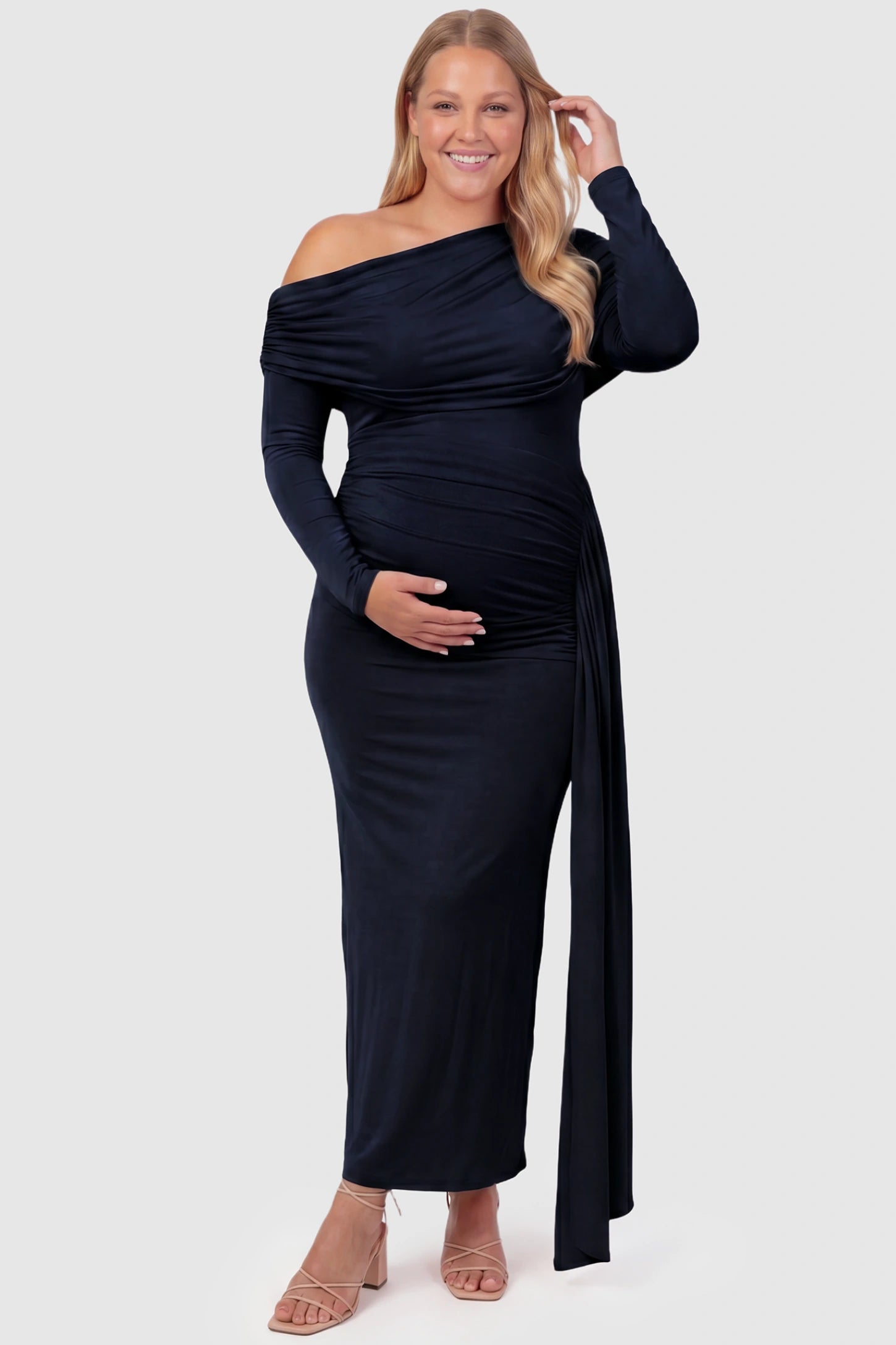 Off Shoulder Draped Wrap Bodycon Maternity Maxi Dress Off Shoulder Draped Wrap Bodycon Maternity Maxi Dress in Navy Blue featuring side ruching and long sleeves on a plus size pregnant model, front view.