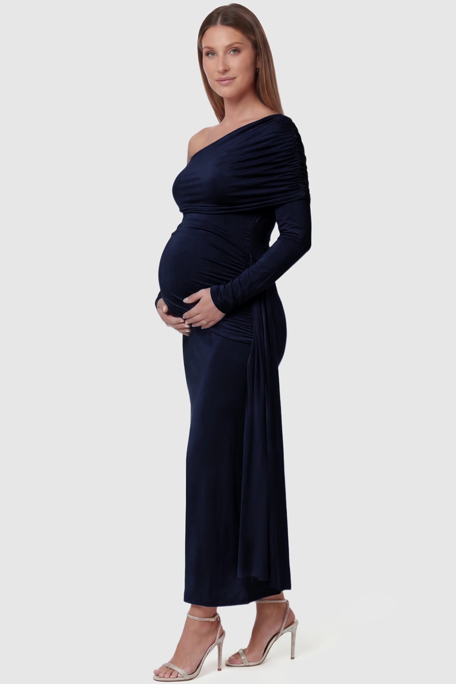 Off Shoulder Draped Wrap Bodycon Maternity Maxi Dress Off Shoulder Draped Wrap Bodycon Maternity Maxi Dress in Navy Blue featuring side ruching and long sleeves on a pregnant model side view.