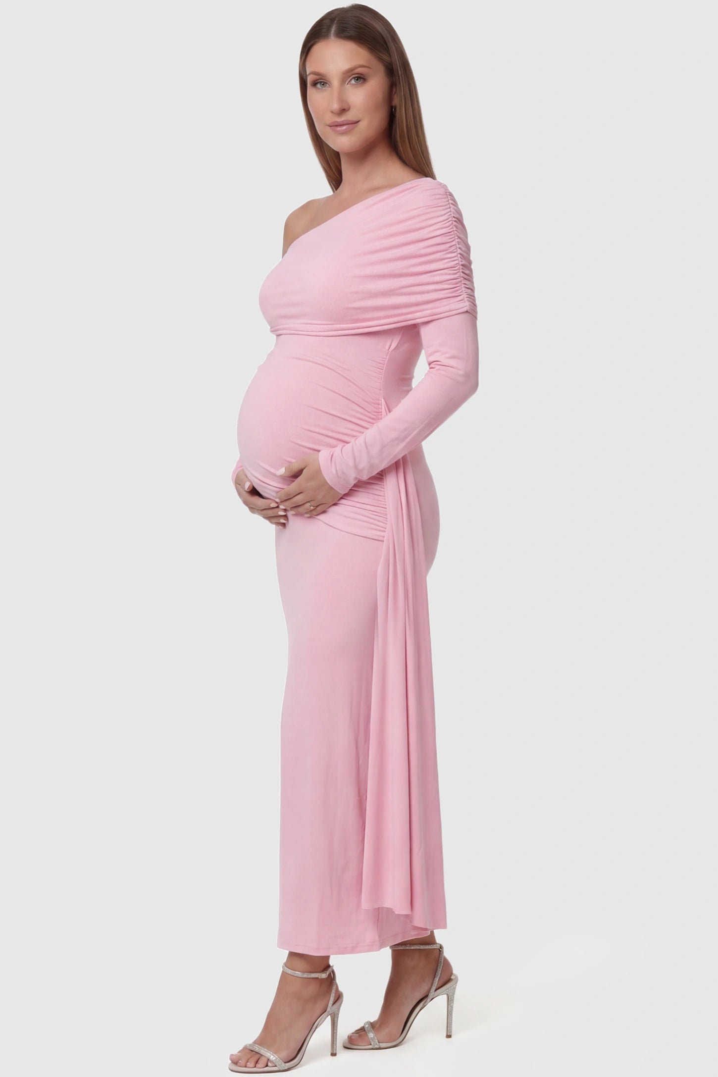 Off Shoulder Draped Wrap Bodycon Maternity Maxi Dress Off Shoulder Draped Wrap Bodycon Maternity Maxi Dress in Pink featuring side ruching and long sleeves on a pregnant model side view.