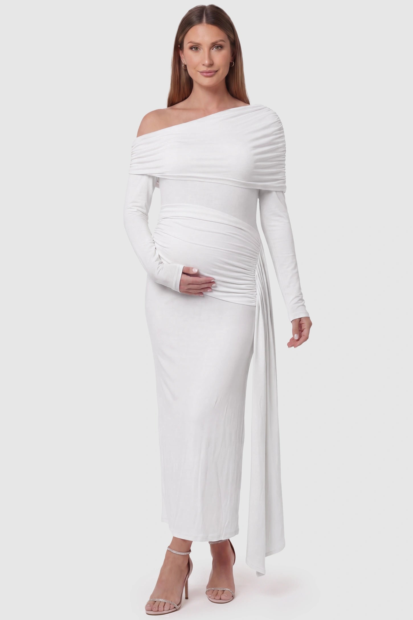Off Shoulder Draped Wrap Bodycon Maternity Maxi Dress Off Shoulder Draped Wrap Bodycon Maternity Maxi Dress in White featuring side ruching and long sleeves on a pregnant model, front view.