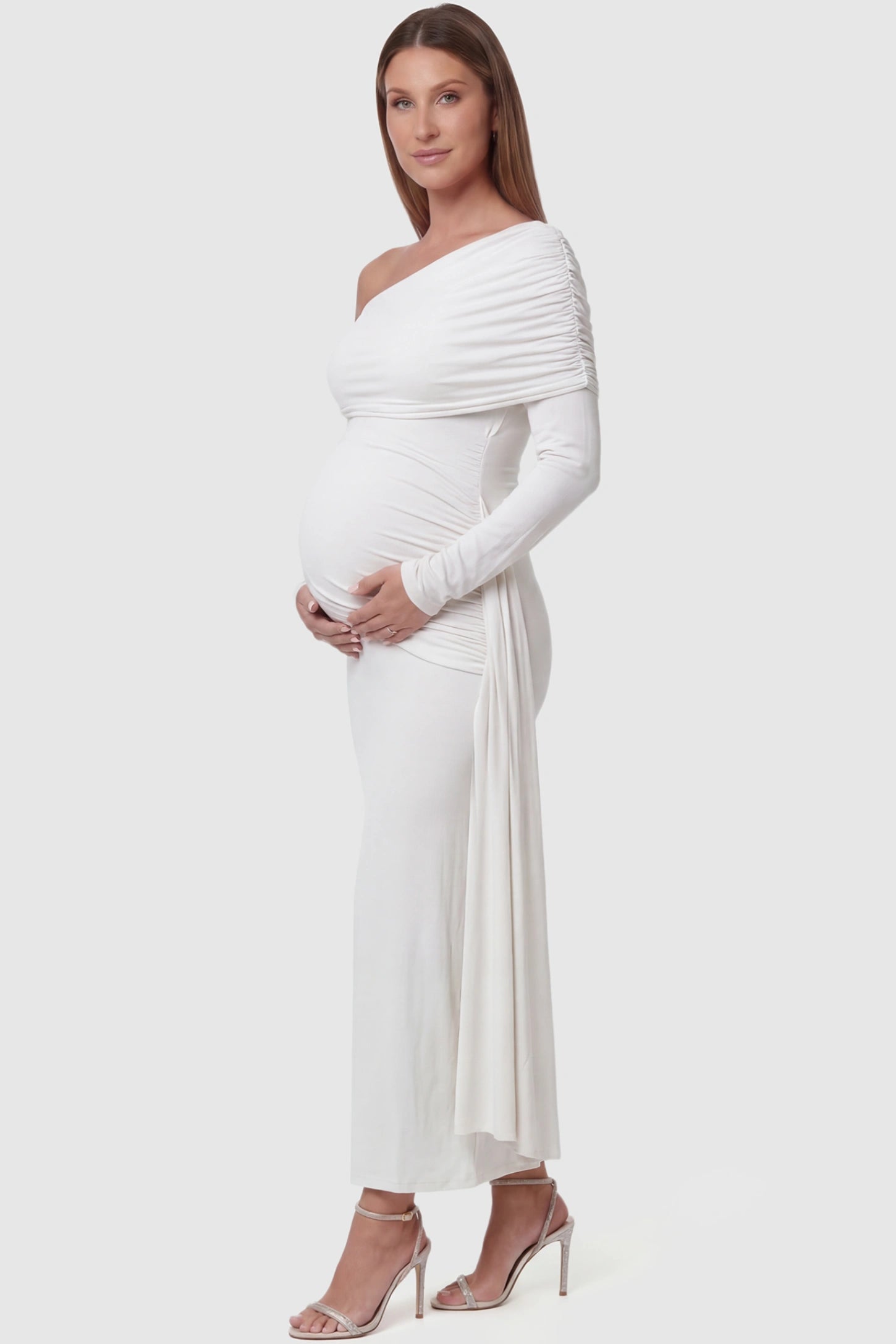 Off Shoulder Draped Wrap Bodycon Maternity Maxi Dress Off Shoulder Draped Wrap Bodycon Maternity Maxi Dress in White featuring side ruching and long sleeves on a pregnant model side view.