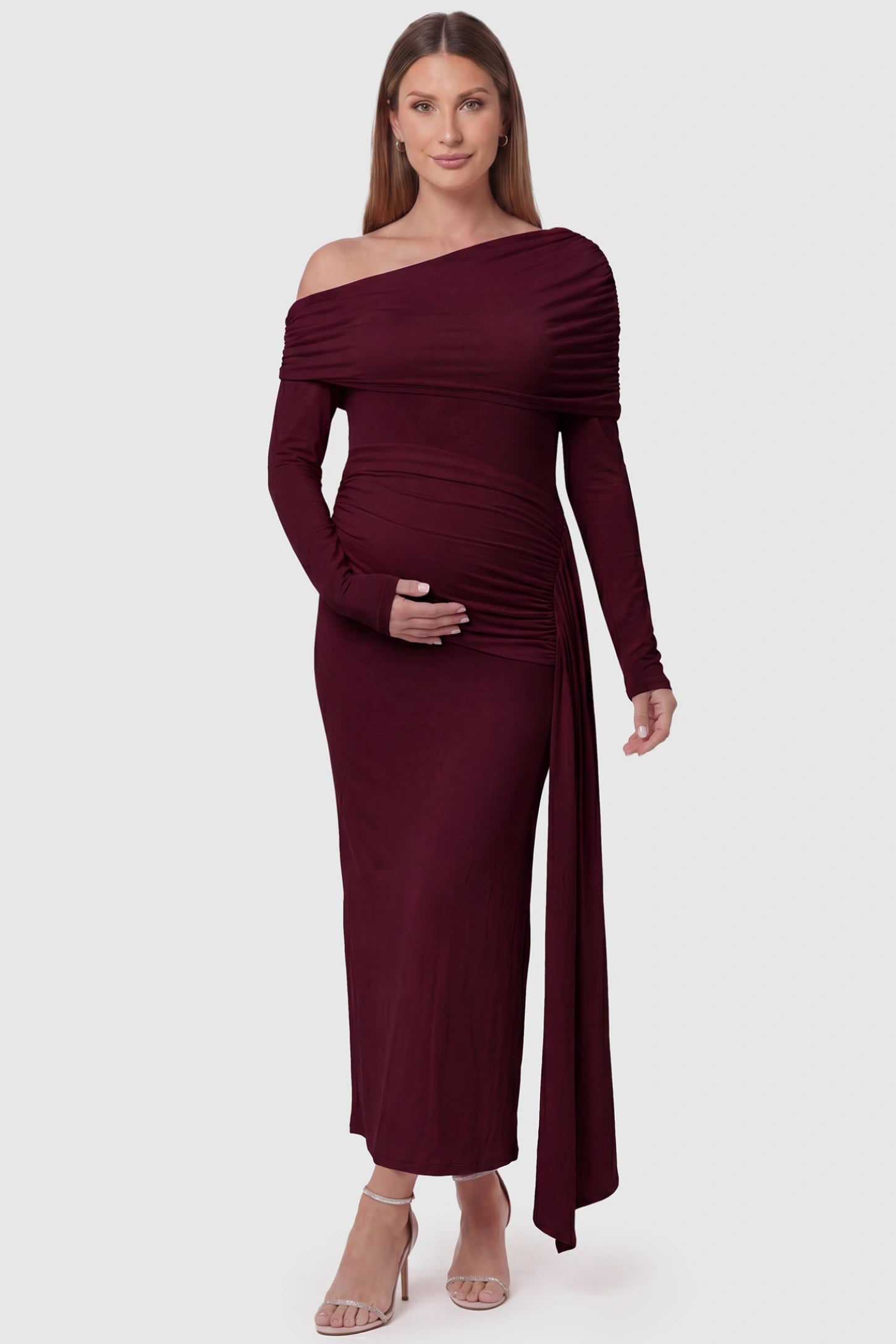 Off Shoulder Draped Wrap Bodycon Maternity Maxi Dress Off Shoulder Draped Wrap Bodycon Maternity Maxi Dress in Wine Red featuring side ruching and long sleeves on a pregnant model, front view.
