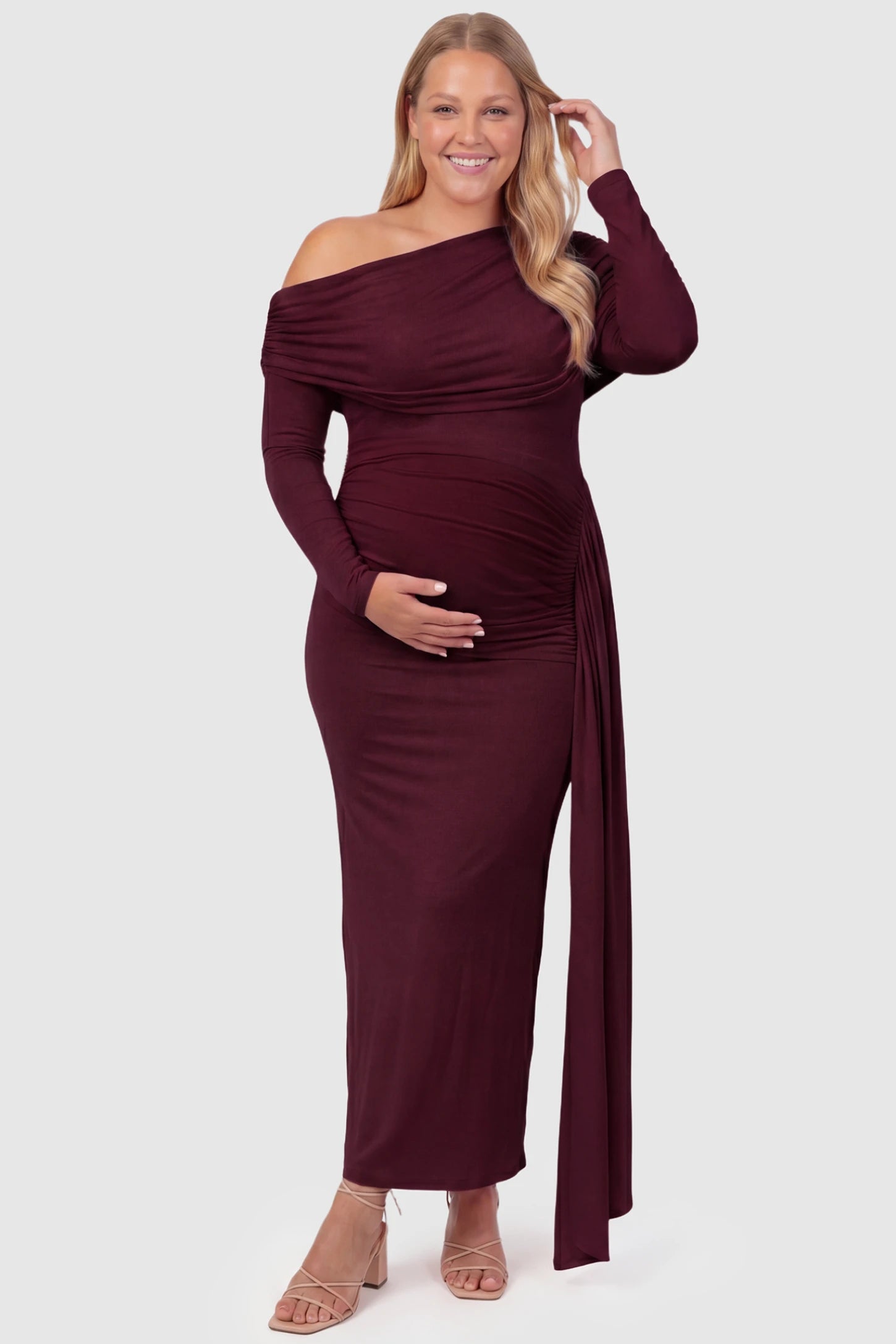 Off Shoulder Draped Wrap Bodycon Maternity Maxi Dress Off Shoulder Draped Wrap Bodycon Maternity Maxi Dress in Wine Red featuring side ruching and long sleeves on a plus size pregnant model, front view.