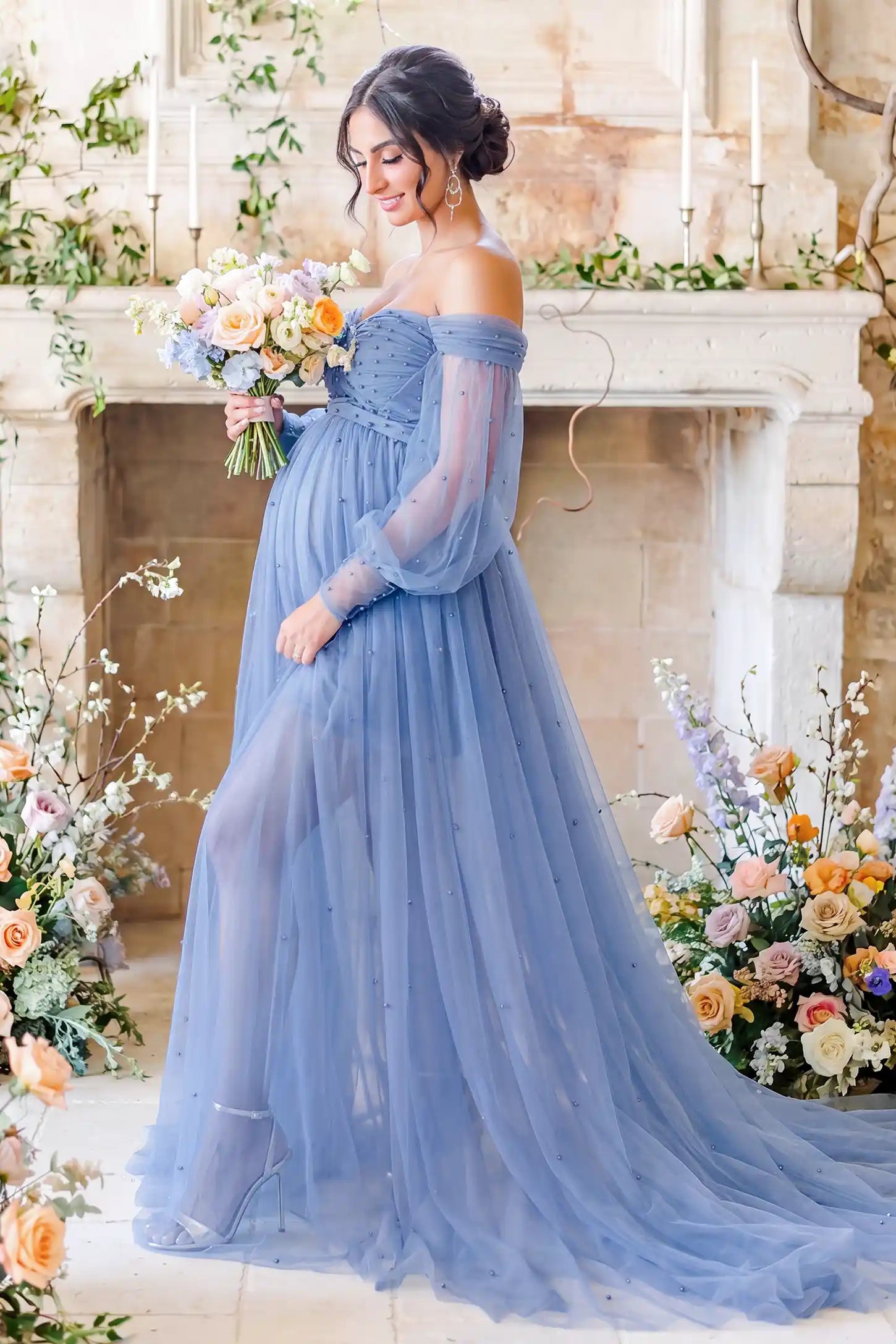 Off-Shoulder Empire Waist Tulle Maternity Gown Off-Shoulder Empire Waist Maternity Gown in Blue highlighting the empire waist, outdoor lifestyle side view on a pregnant model.