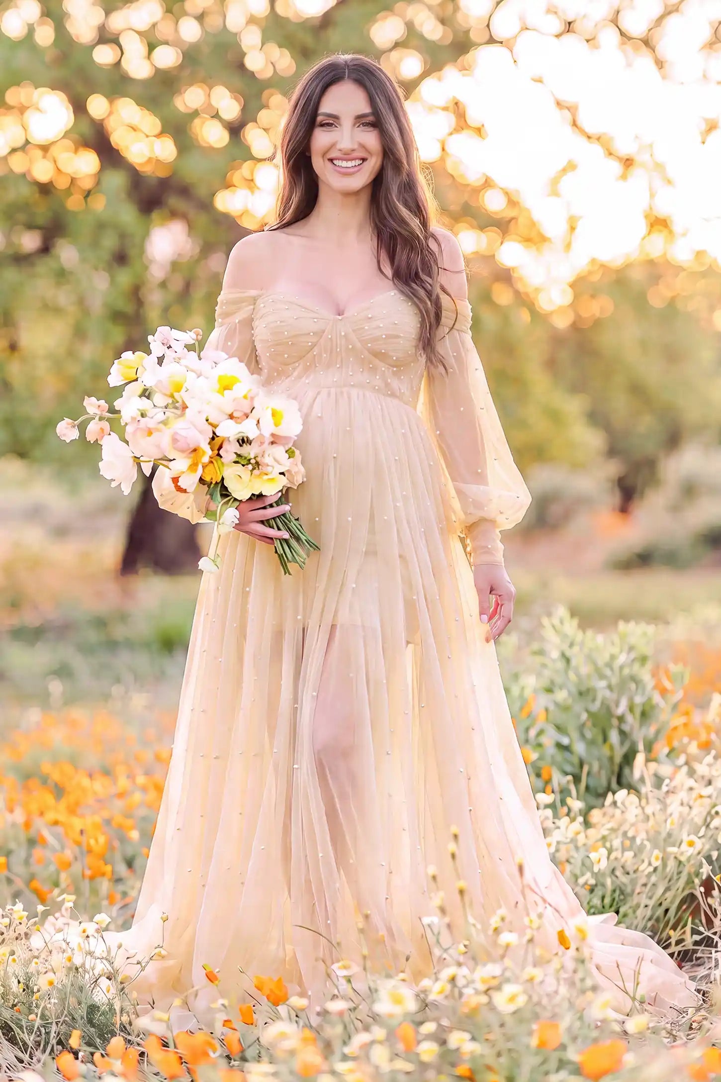 Off-Shoulder Empire Waist Tulle Maternity Gown Off-Shoulder Empire Waist Maternity Gown in Camel featuring an off-shoulder sweetheart neckline, outdoor lifestyle front view on a pregnant model.
