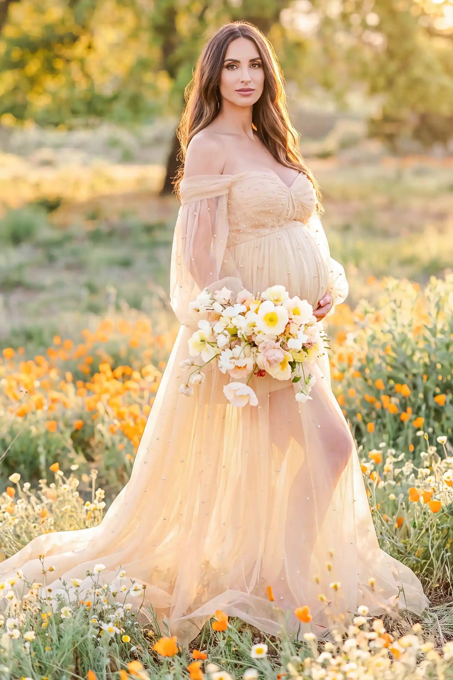 Off-Shoulder Empire Waist Tulle Maternity Gown Off-Shoulder Empire Waist Maternity Gown in Camel highlighting the empire waist, outdoor lifestyle side view on a pregnant model.